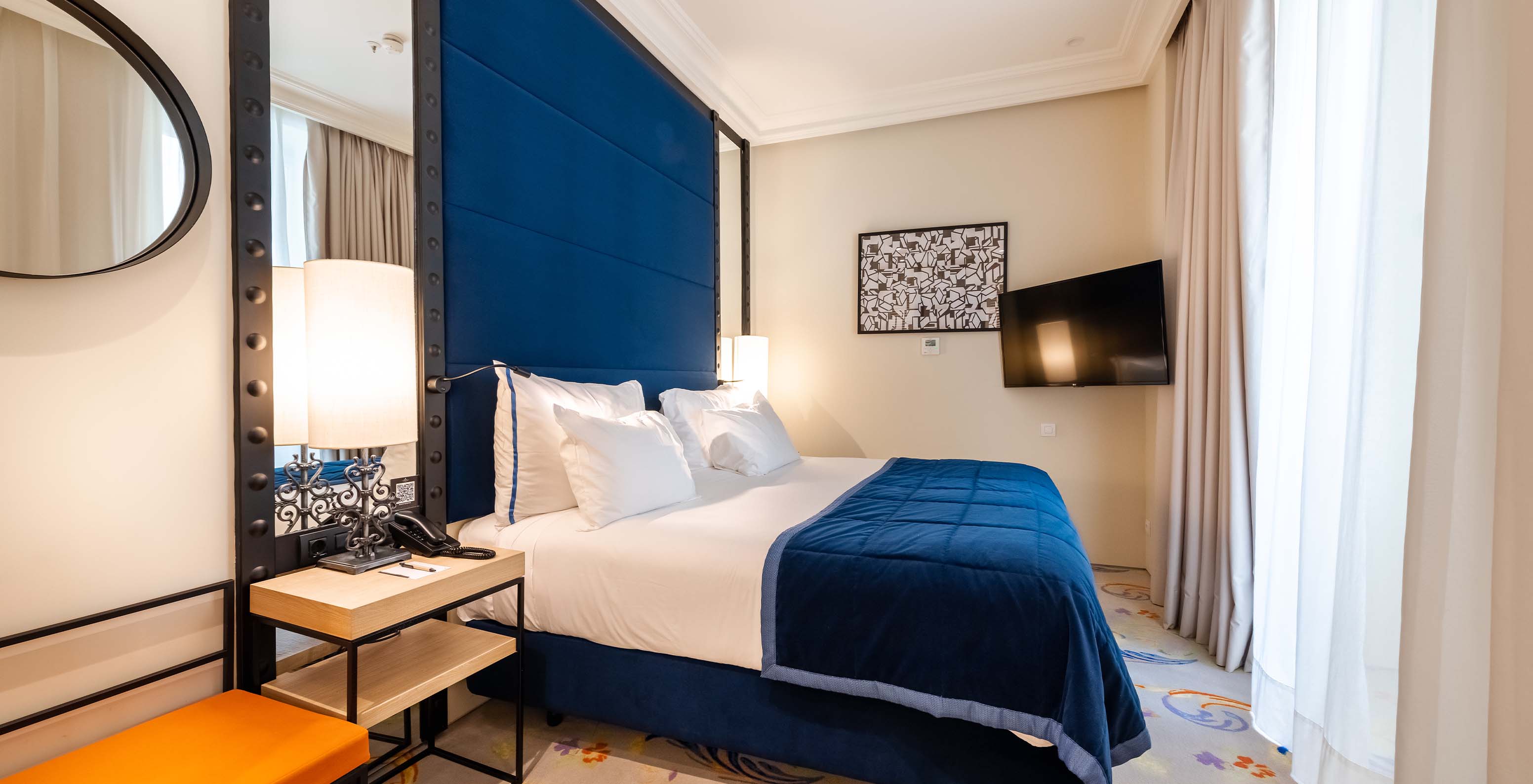 The Suite at Pestana Collection Plaza Mayor has a double bed, bedside table, TV on the wall and window with curtains