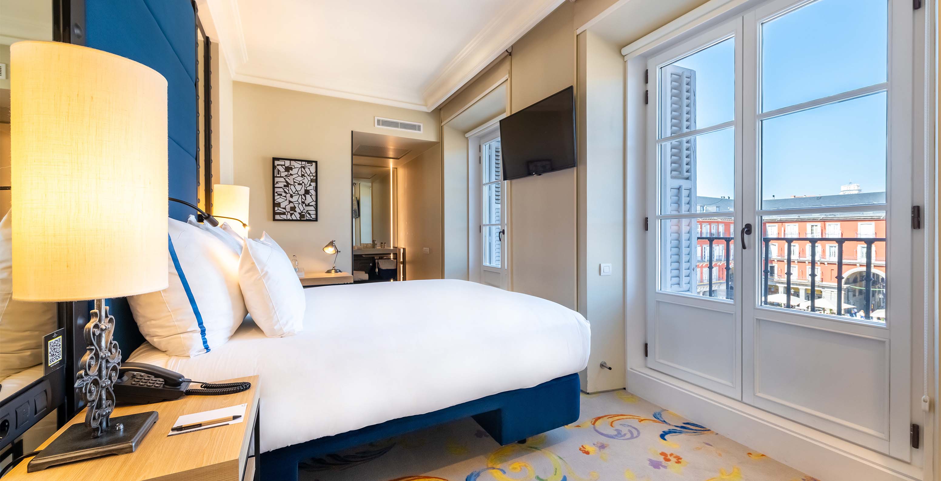 The Deluxe Grand Plaza Mayor at Pestana Collection Plaza Mayor has a double bed and a window with a view of Plaza Mayor
