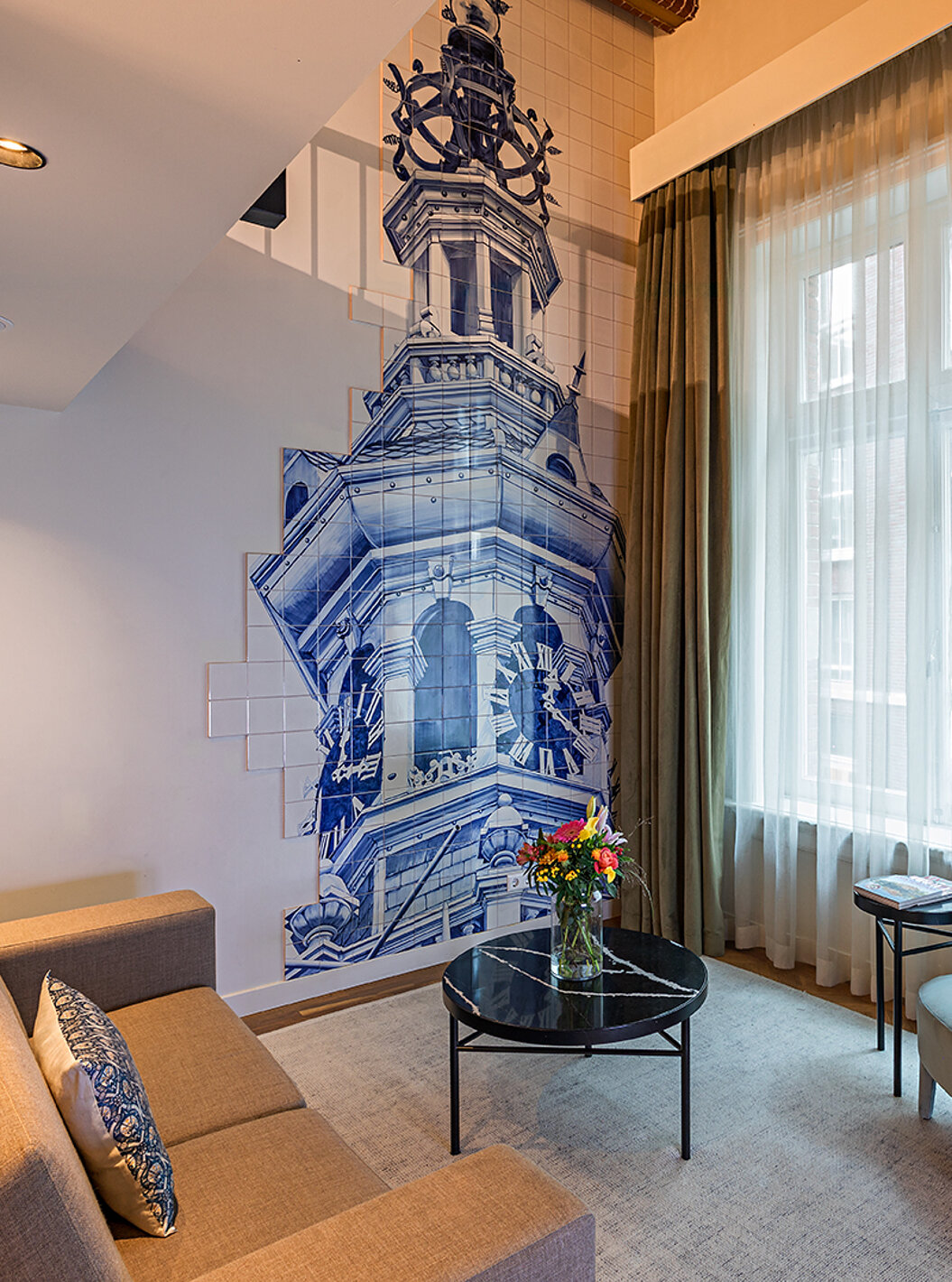 Mezzanine Suite at Pestana Amsterdam Riverside has a living room with sofa, coffee table with flowers, and tiles
