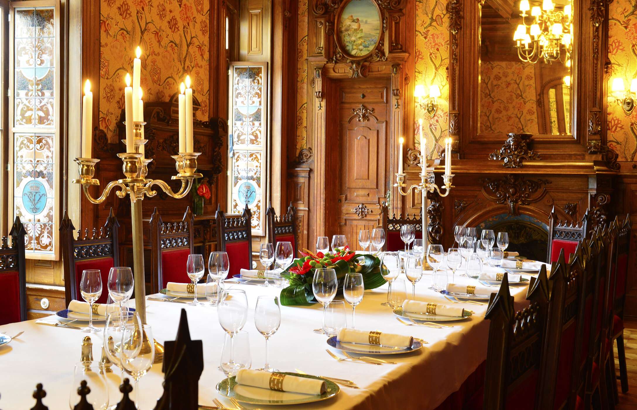 Wedding in an impressive room with elegant decor, featuring a long table with floral arrangements and carved wooden walls