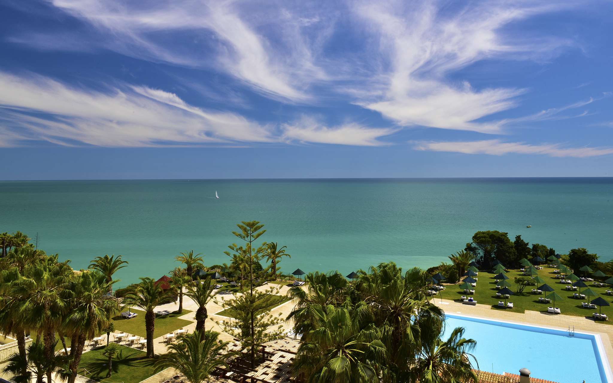 Panoramic exterior view of Pestana Viking, surrounded by palm trees around the outdoor pool, with direct beach access