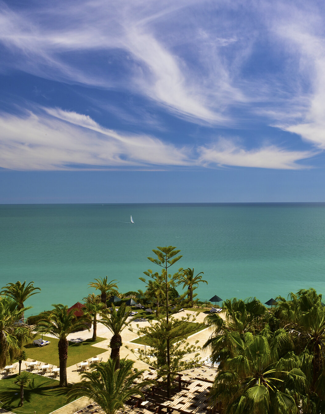 Panoramic exterior view of Pestana Viking, surrounded by palm trees around the outdoor pool, with direct beach access