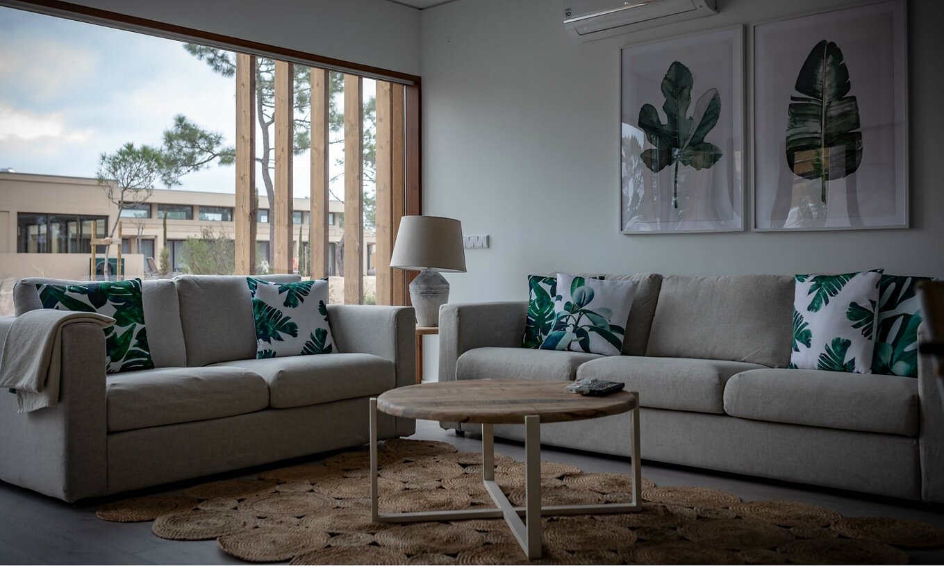 El Apartamento Eco Village Planta Baja del Pestana Tróia Eco Resort tiene una sala con dos sofás, mesa y cuadro de hojas