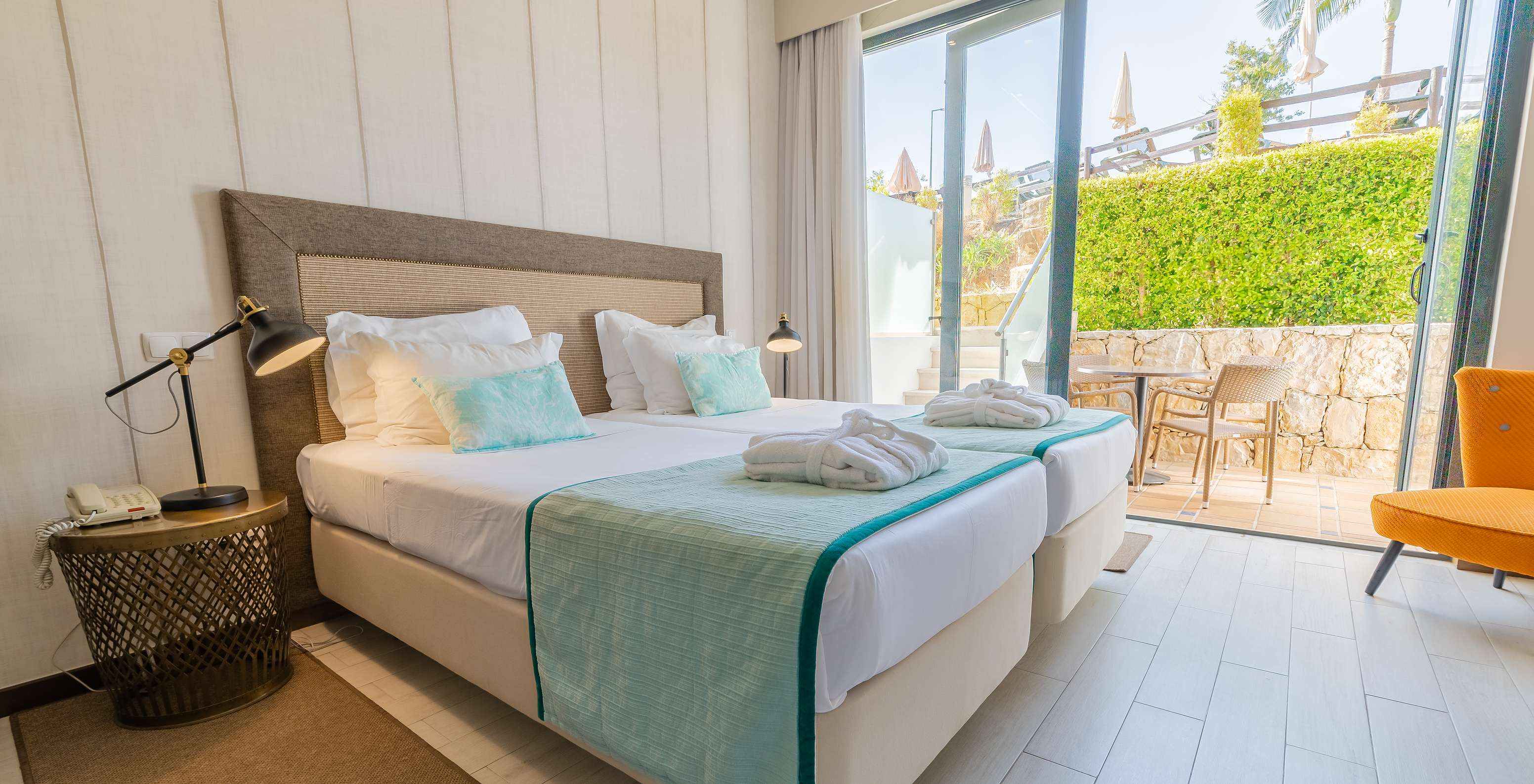 La Suite Garden del Pestana Alvor Park tiene dos camas, un sillón, cortinas y un balcón con mesa y sillas