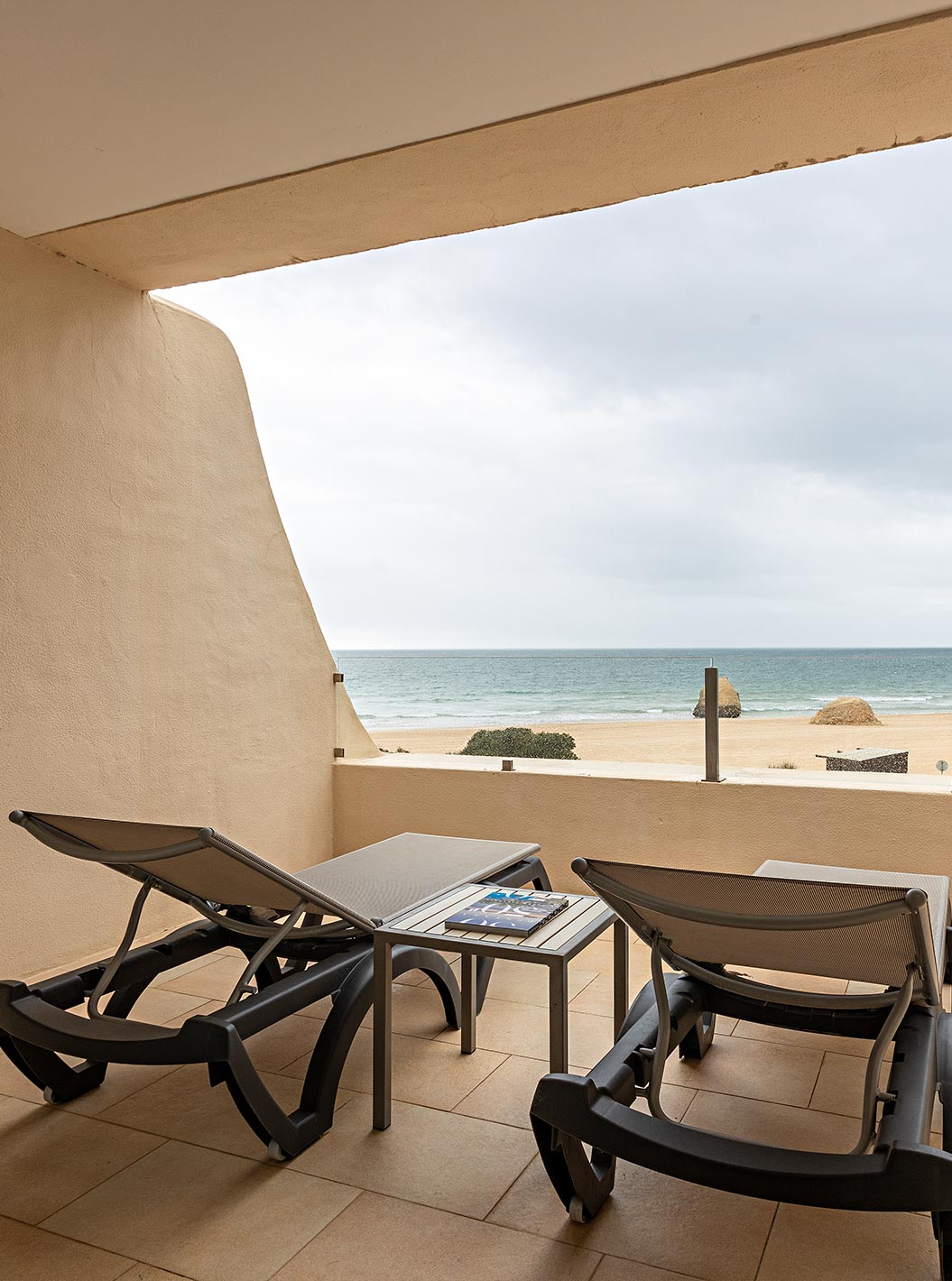La Suite Cliff T1 en Pestana Alvor Praia tiene un balcón con dos tumbonas y vista a la playa