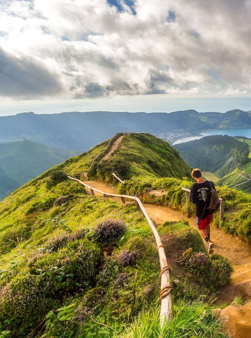 Hombre camina por un sendero de tierra con vista a la Laguna de las Siete Ciudades, Isla de São Miguel, Azores