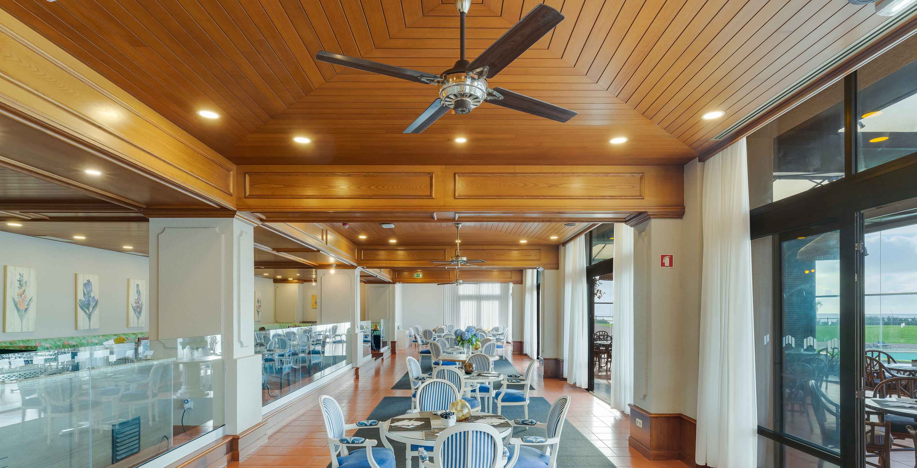 Restaurante Lugar da Praia en Pestana Bahia Praia con mesas, sillas, techo de madera y grandes ventanas con vista