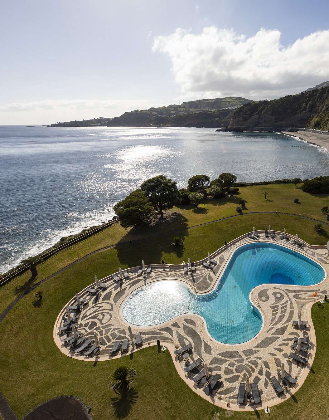 Piscina con vistas al mar y la playa en el Pestana Bahia Praia en São Miguel en un día parcialmente nublado