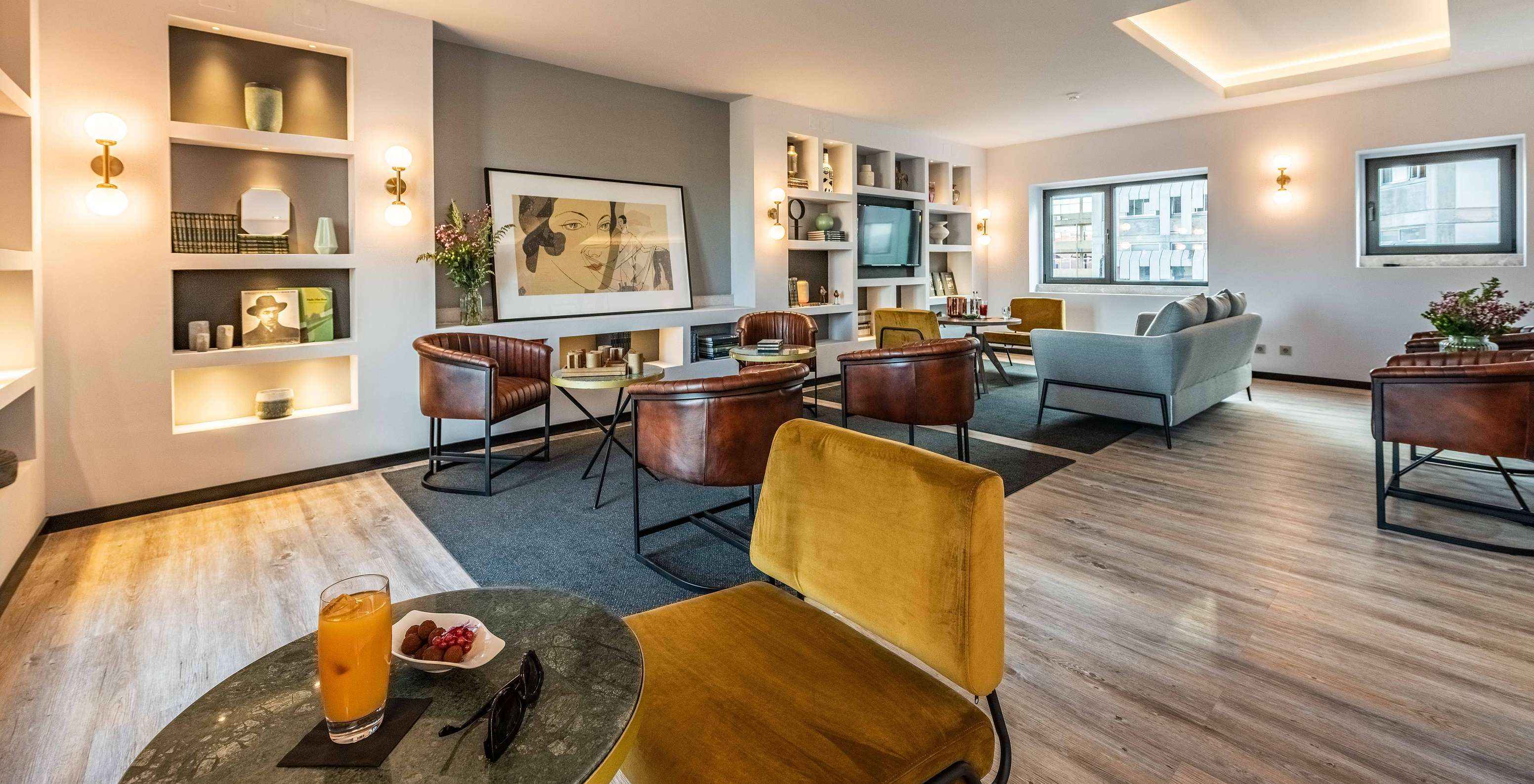 Lounge con sofás, sillas, mesas, cuadros, televisión, alfombras y objetos de decoración con ventanas con vista a la ciudad