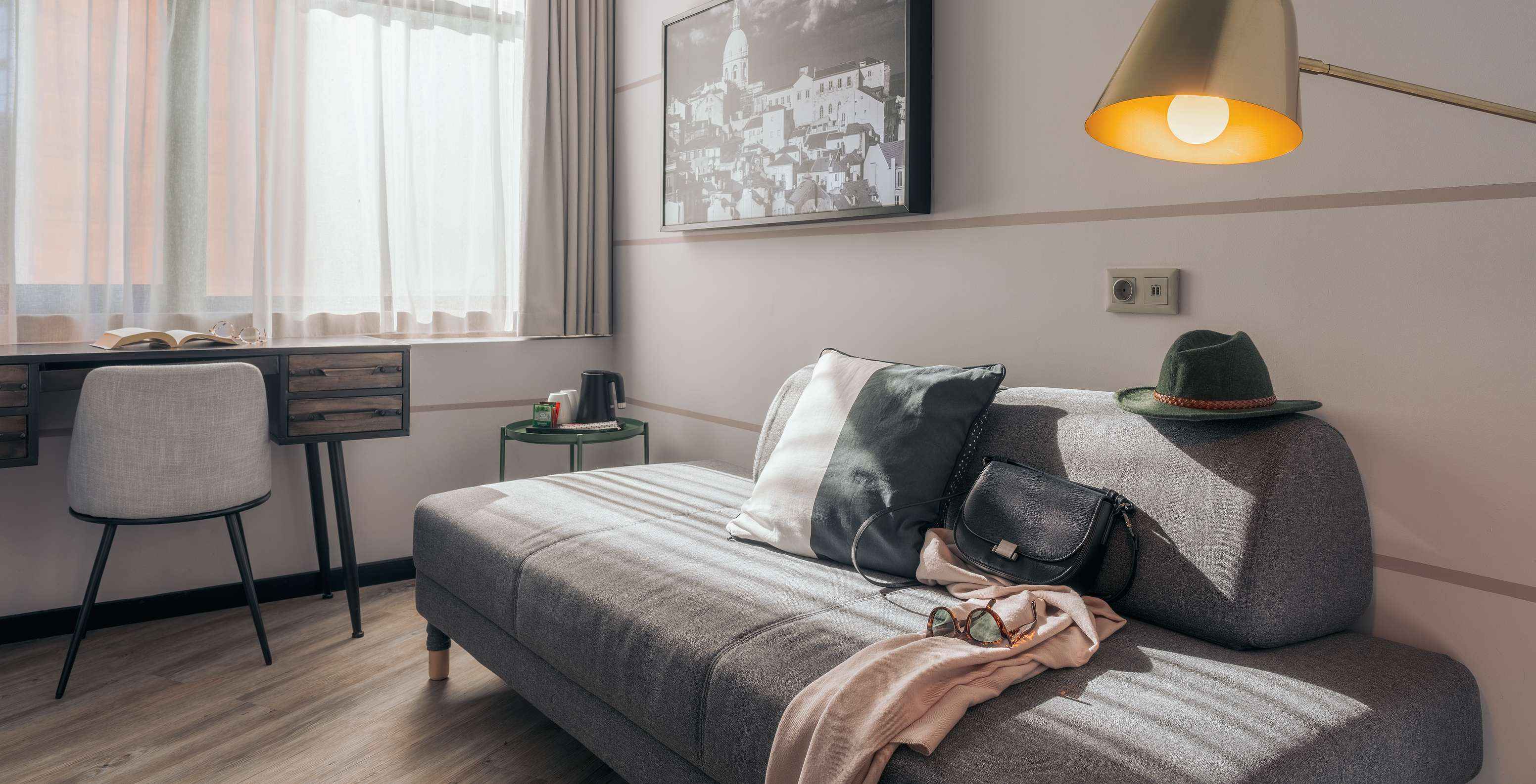 El Double Superior del Pestana Lisboa Vintage tiene un sofá gris, un escritorio con silla, una mesa auxiliar y un cuadro