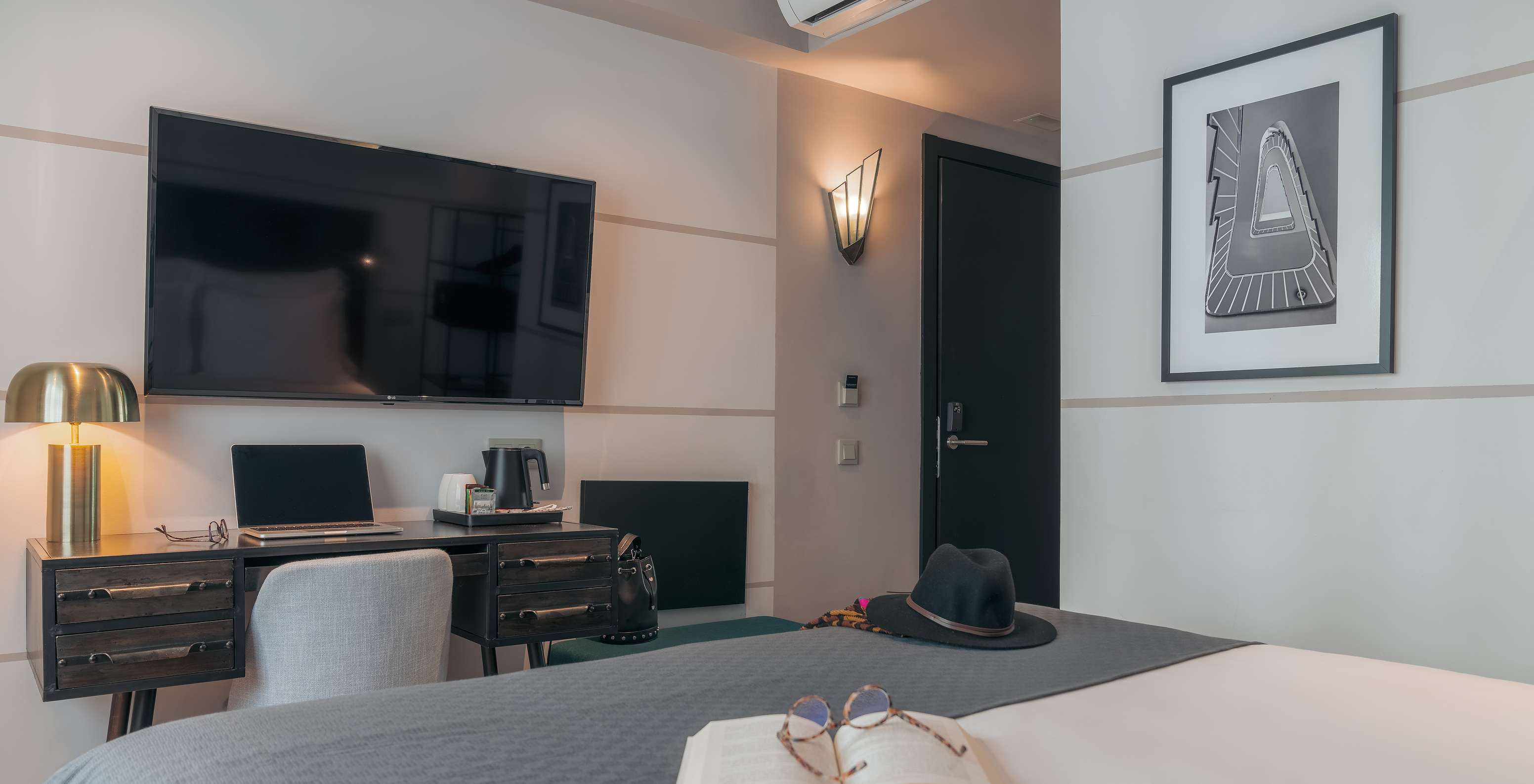 El Vintage del Pestana Lisboa Vintage tiene una cama con una manta gris, un escritorio con computadora y televisor