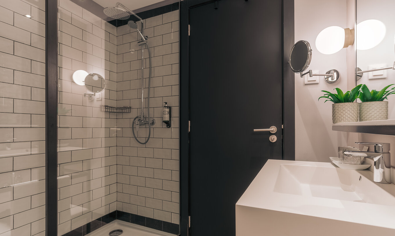La Rooftop Junior Suite del Pestana Lisboa Vintage tiene un baño con ducha con puertas de vidrio y dos espejos