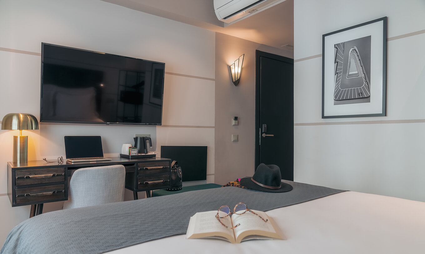 El Vintage del Pestana Lisboa Vintage tiene una cama con una manta gris, un escritorio con computadora y televisor