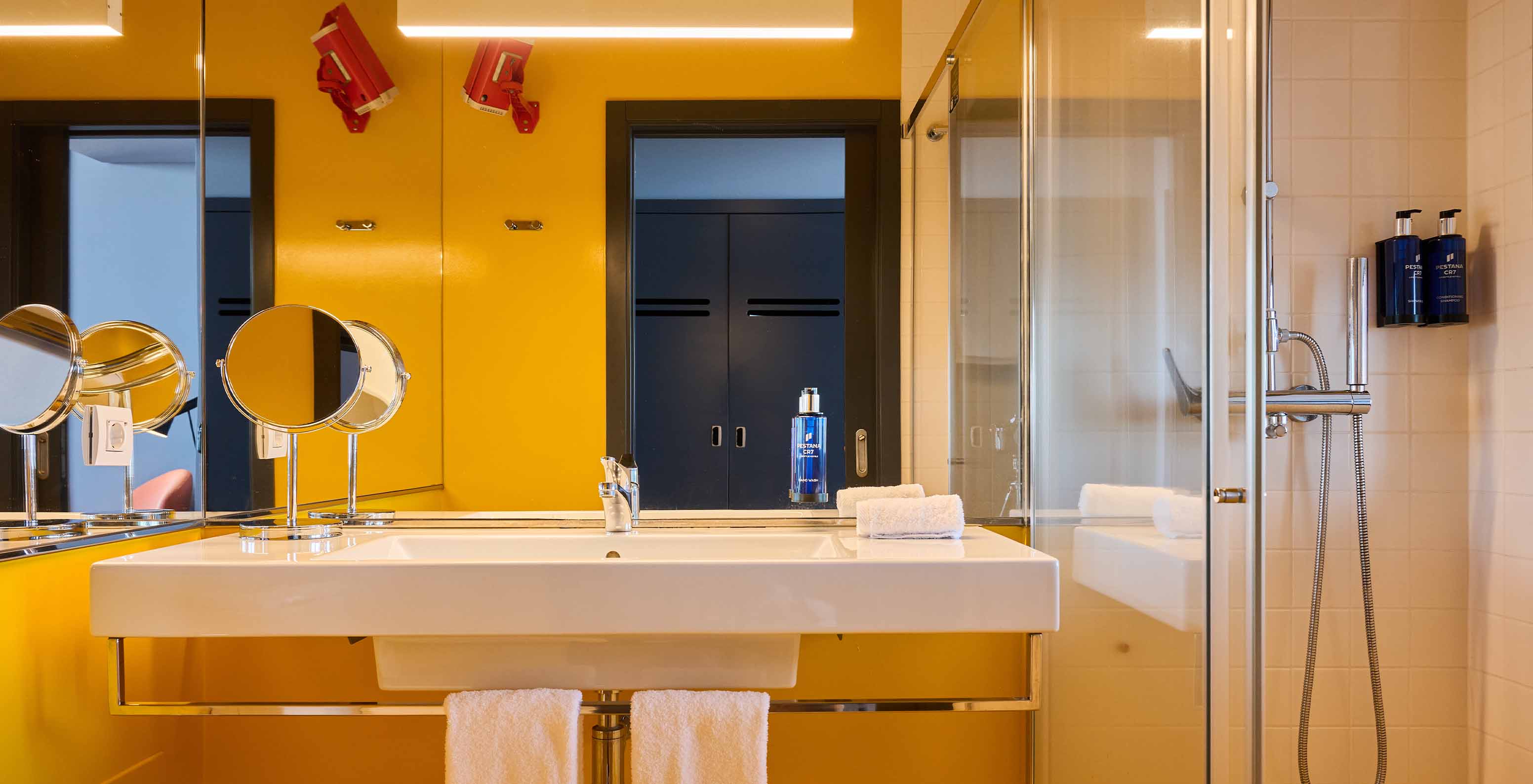 La Habitación CR Superior del Pestana CR7 Funchal tiene un baño con aire moderno, en tonos amarillos, una ducha