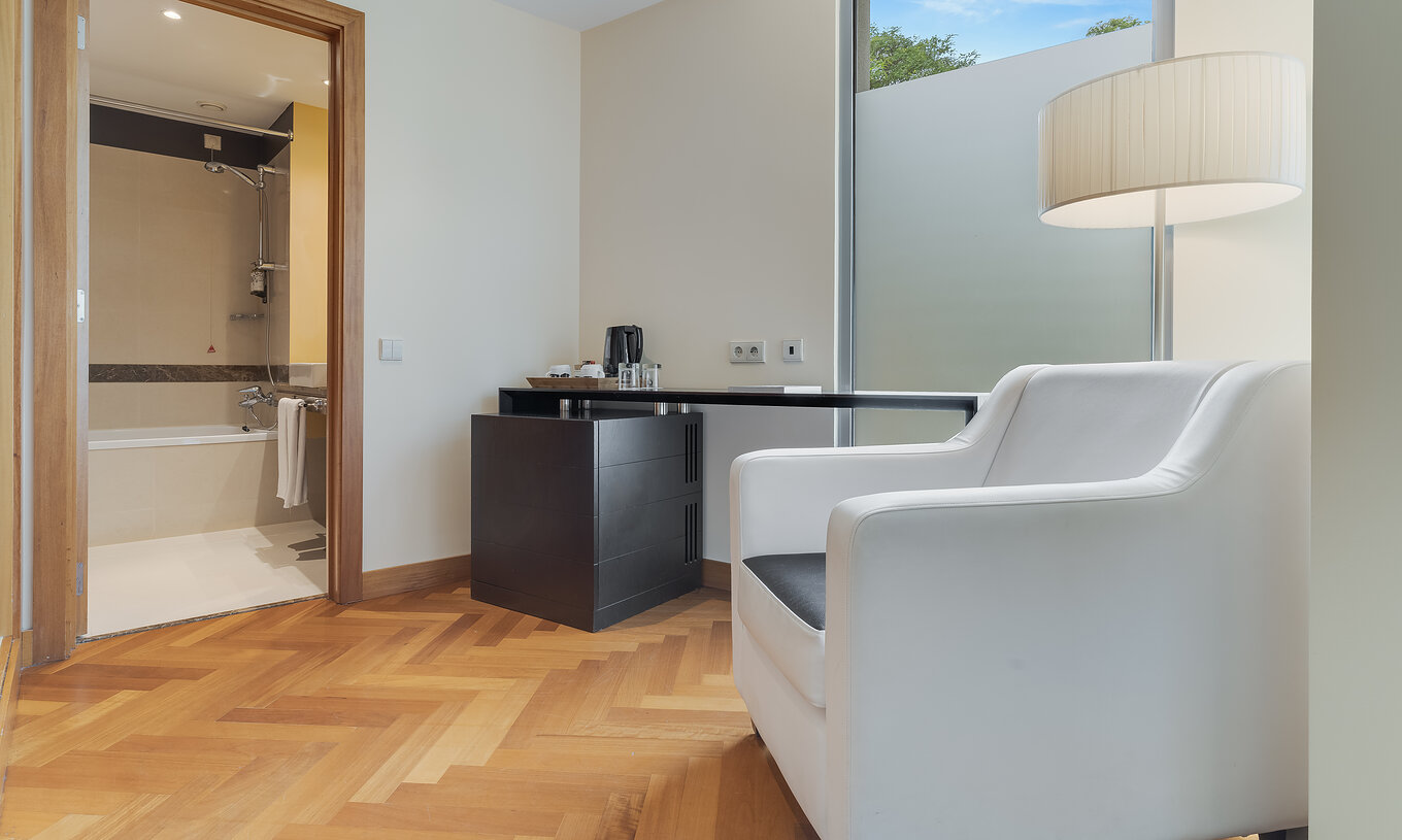 El Twin Clásico del Pestana Promenade tiene un baño con bañera y un sillón y una mesa a la puerta