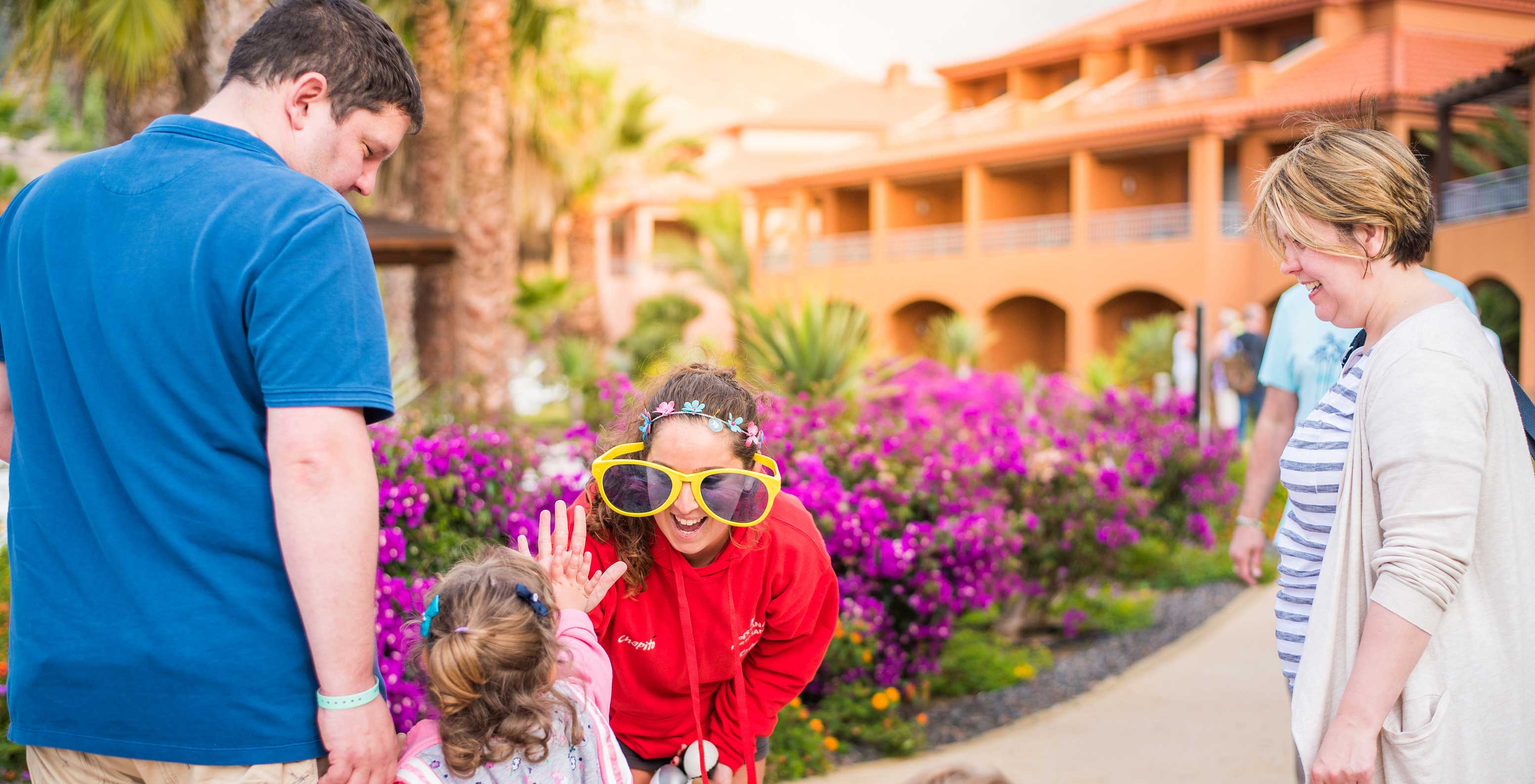 Familia divirtiéndose en Pestana Porto Santo, gafas de sol grandes, flores moradas día soleado