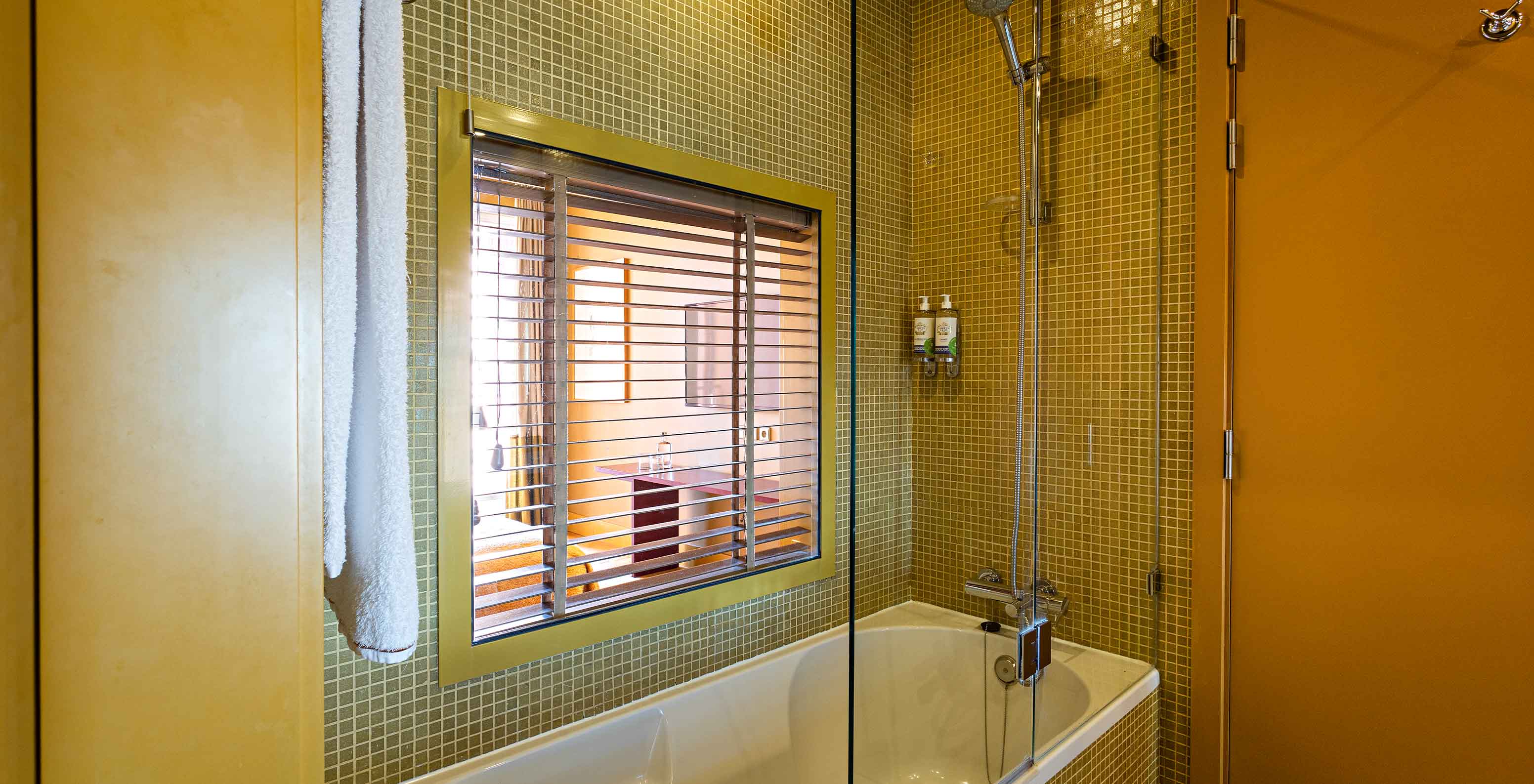 La Suite Balcony tiene un baño con bañera y ventana al dormitorio