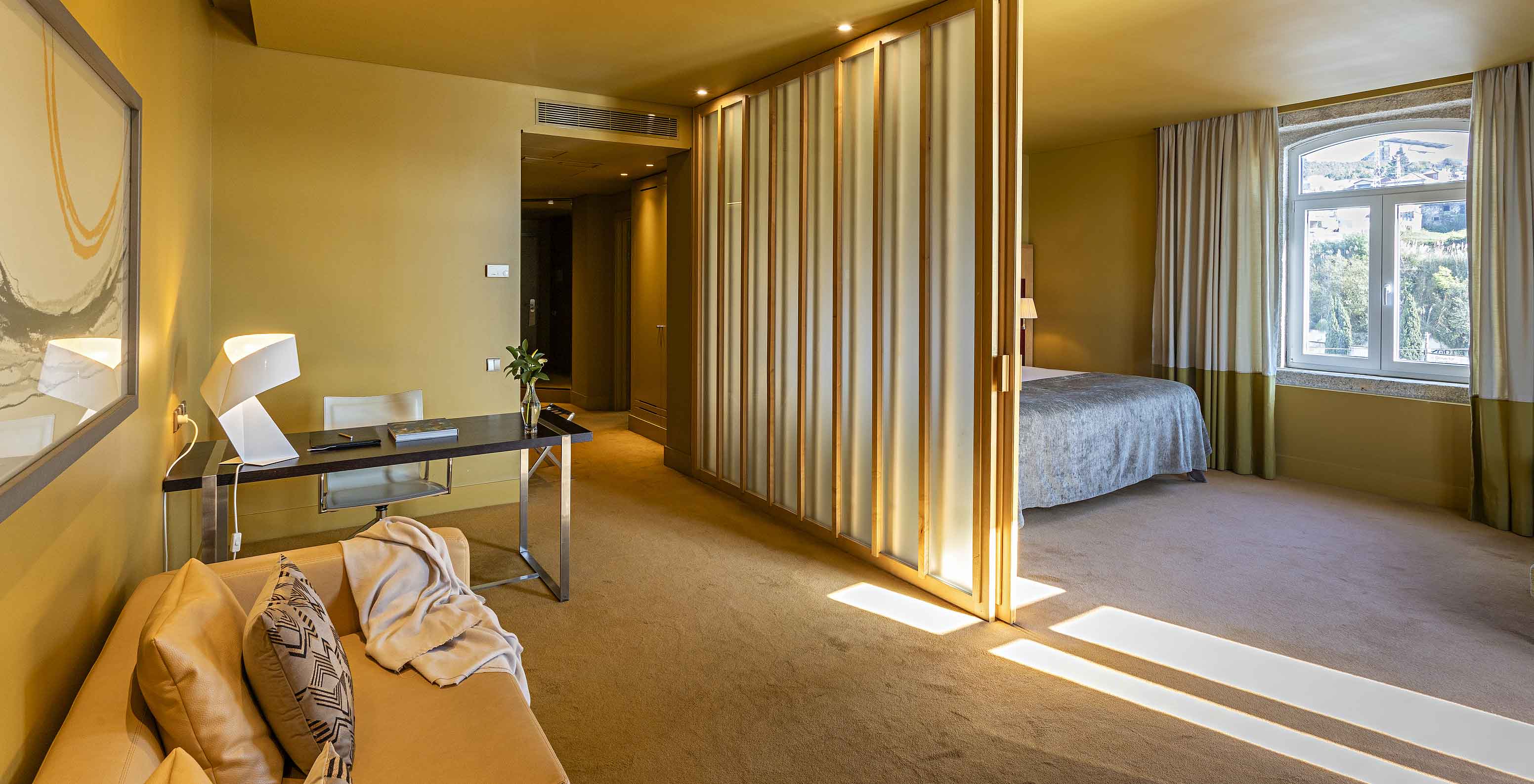 La Standard Suite tiene una cama doble con una separación hacia la sala con sofá y escritorio