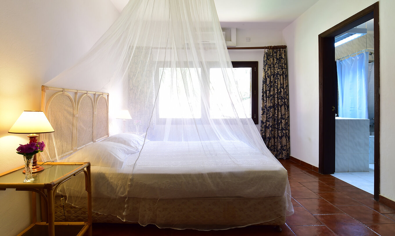 La Suite del Pestana Miramar São Tomé tiene una cama matrimonial con mosquitero, una mesa de noche y una ventana