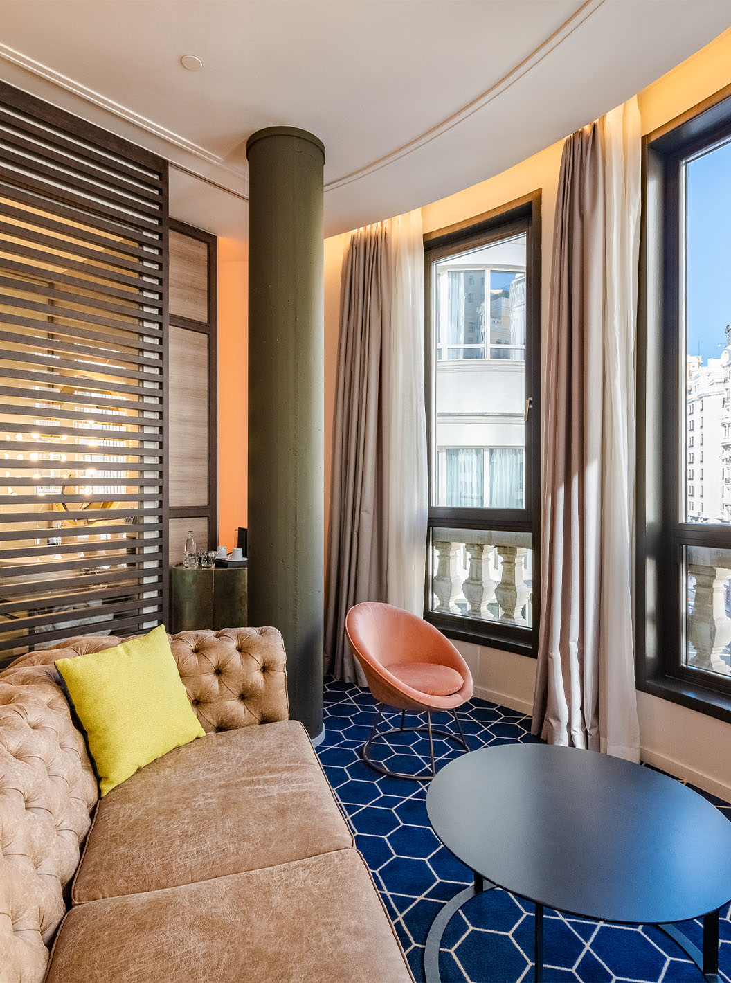 El The Amazing CR7 del Pestana CR7 Gran Vía Madrid tiene un sofá, dos mesas, ventanas grandes con vista a la Gran Vía