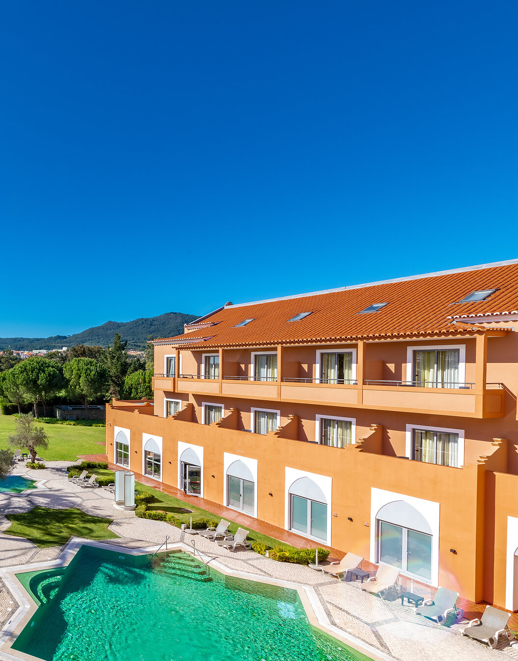 Vista de Pestana Sintra Golf, hotel de 4 estrellas en Sintra, con piscina exterior, jardín con árboles y un campo de golf