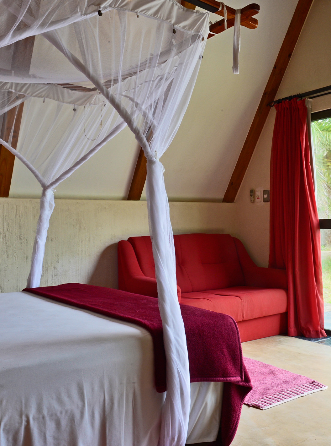 Bungalow Suite T2 van Pestana Bazaruto Lodge heeft bed met hemelbed en uitzicht op tuin en een dubbele bank aan de zijkant
