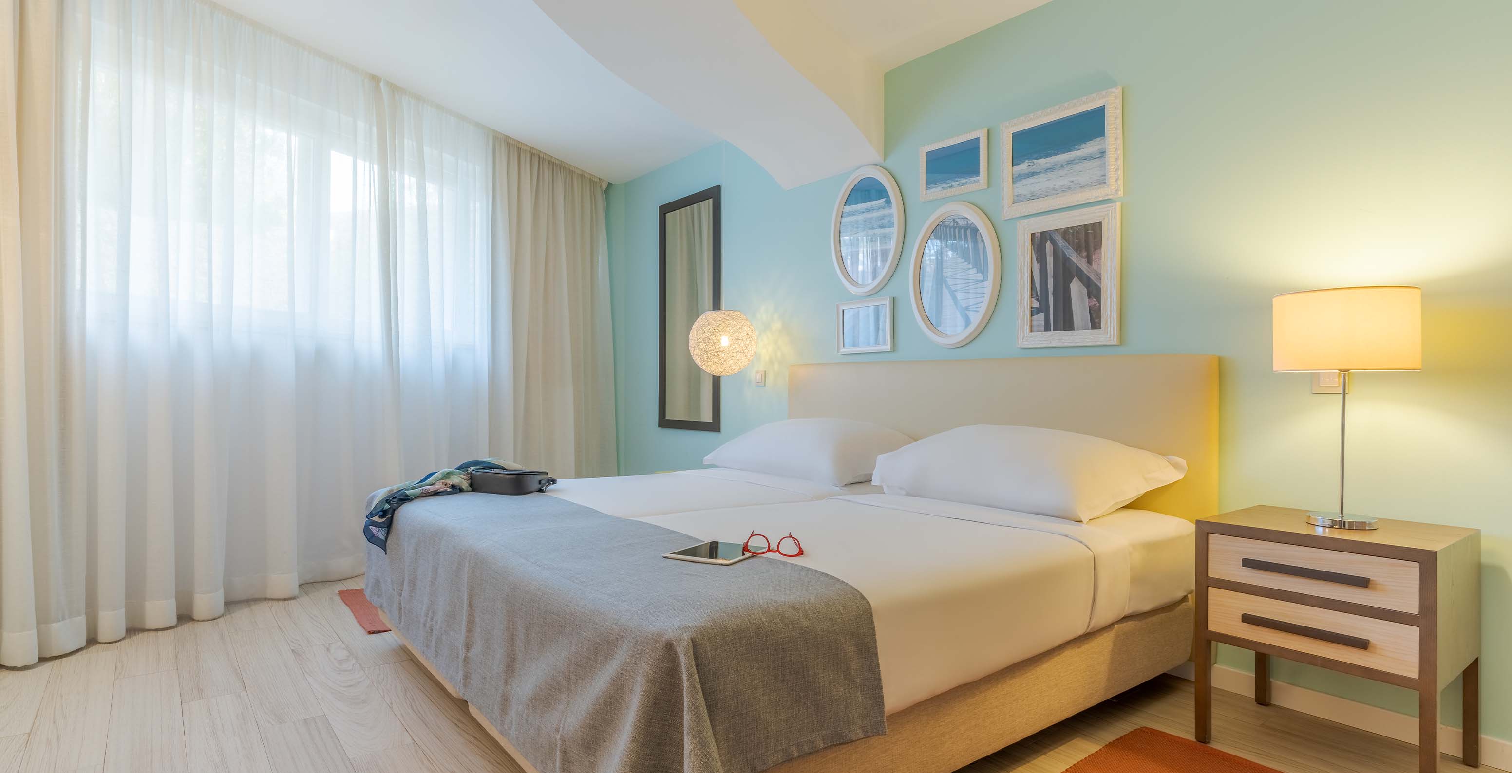 De Suite T1 met uitzicht op de tuin van Pestana Alvor Praia heeft twee bedden, nachtkastje met lamp, tapijt en schilderijen