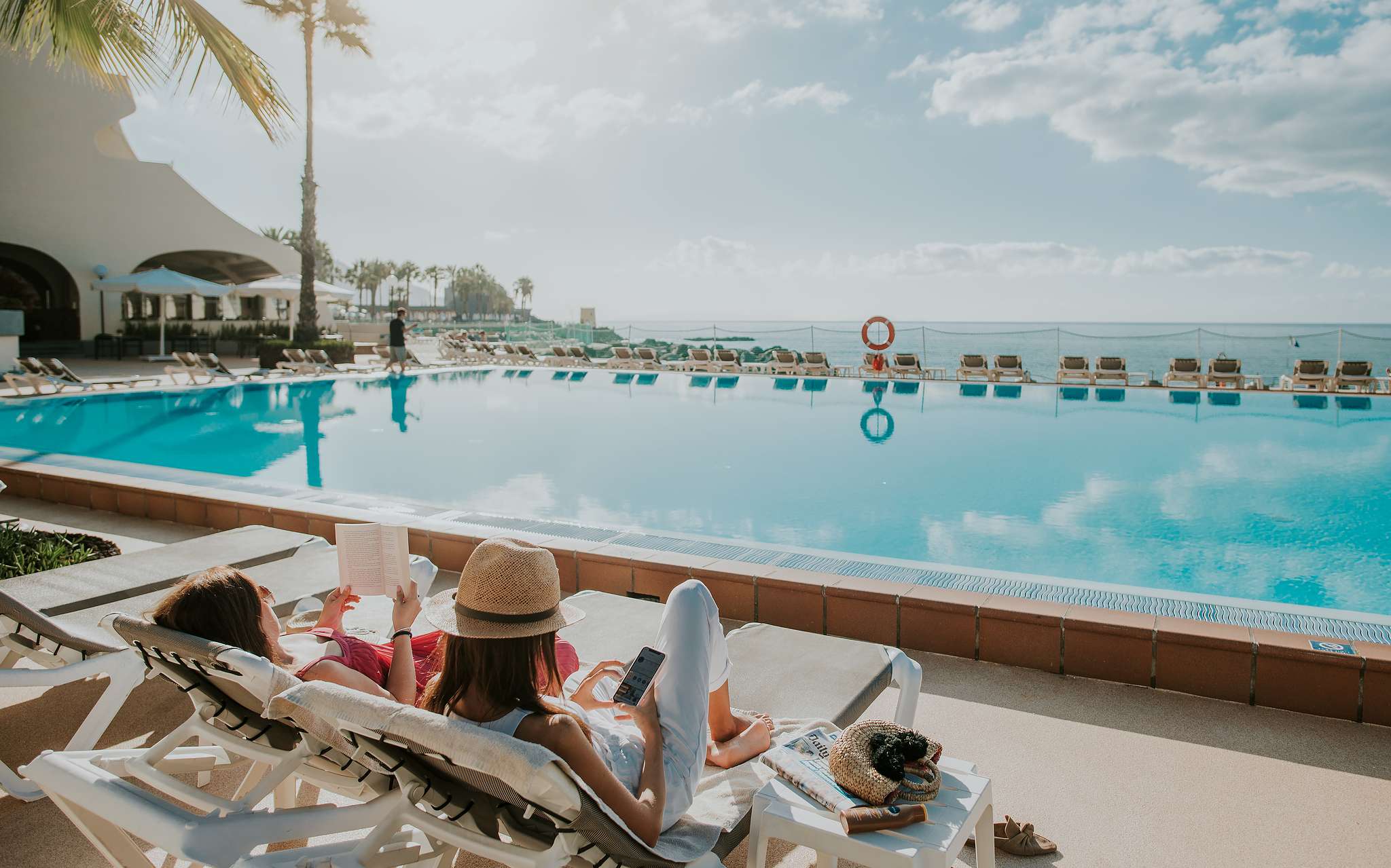 Zwembad Pestana Madeira Beach Club met oceaanzicht, twee dames relaxen op ligstoelen
