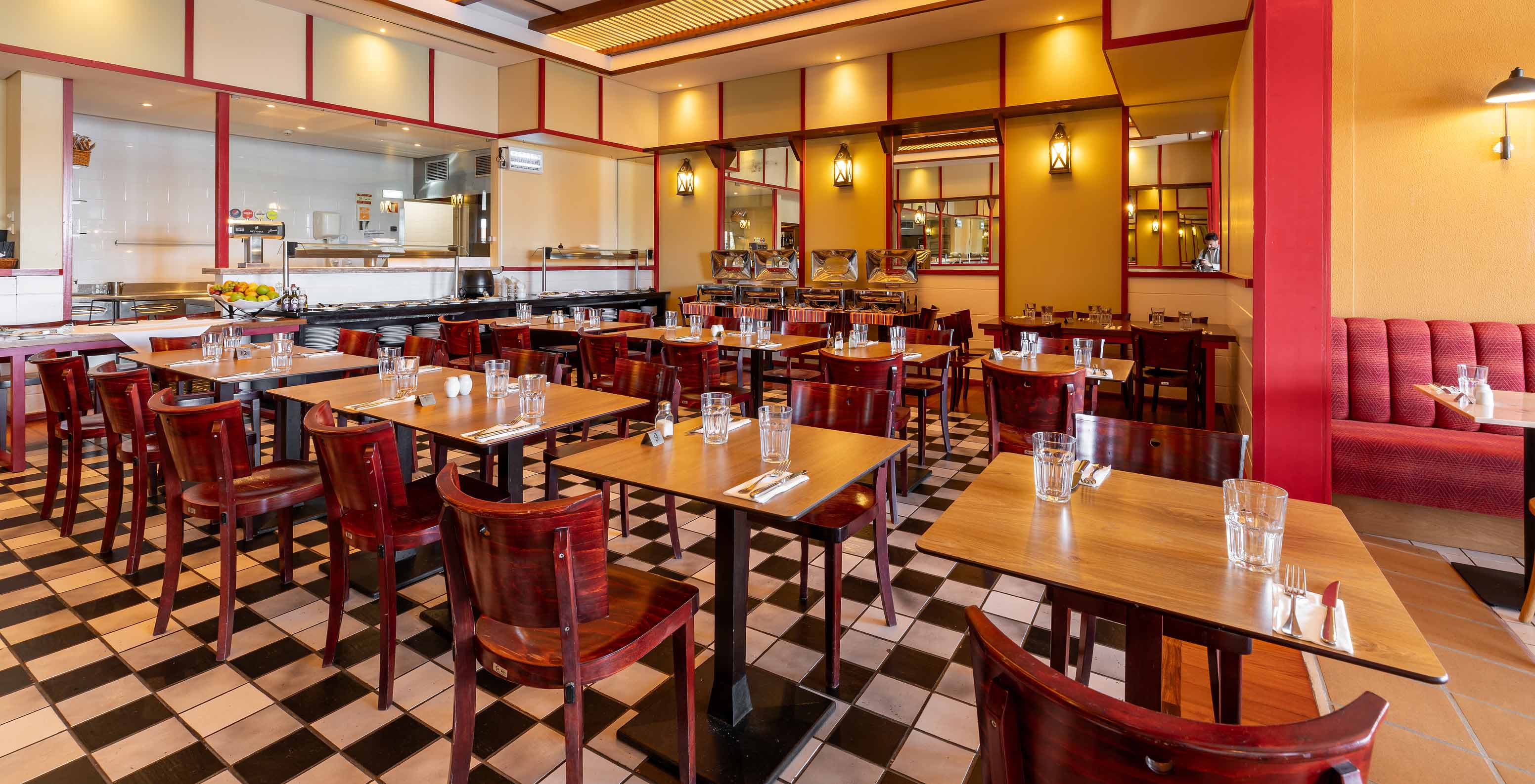 Restaurant Luigi van het 5-sterrenresort op Porto Santo heeft donkere tafels en stoelen met rode accenten.