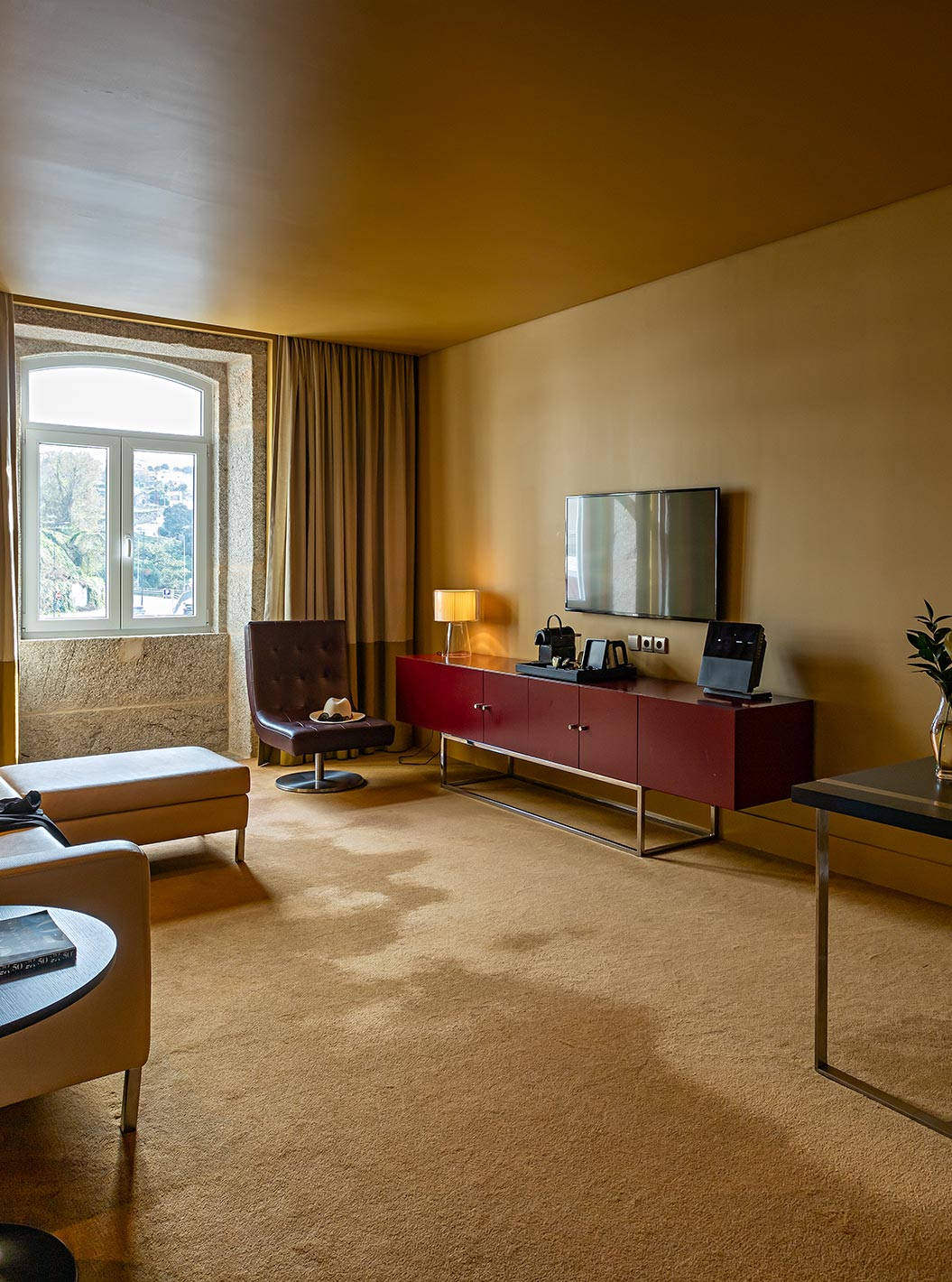 De Junior Suite heeft een kamer met chaise-longue bank, een bureau en een TV