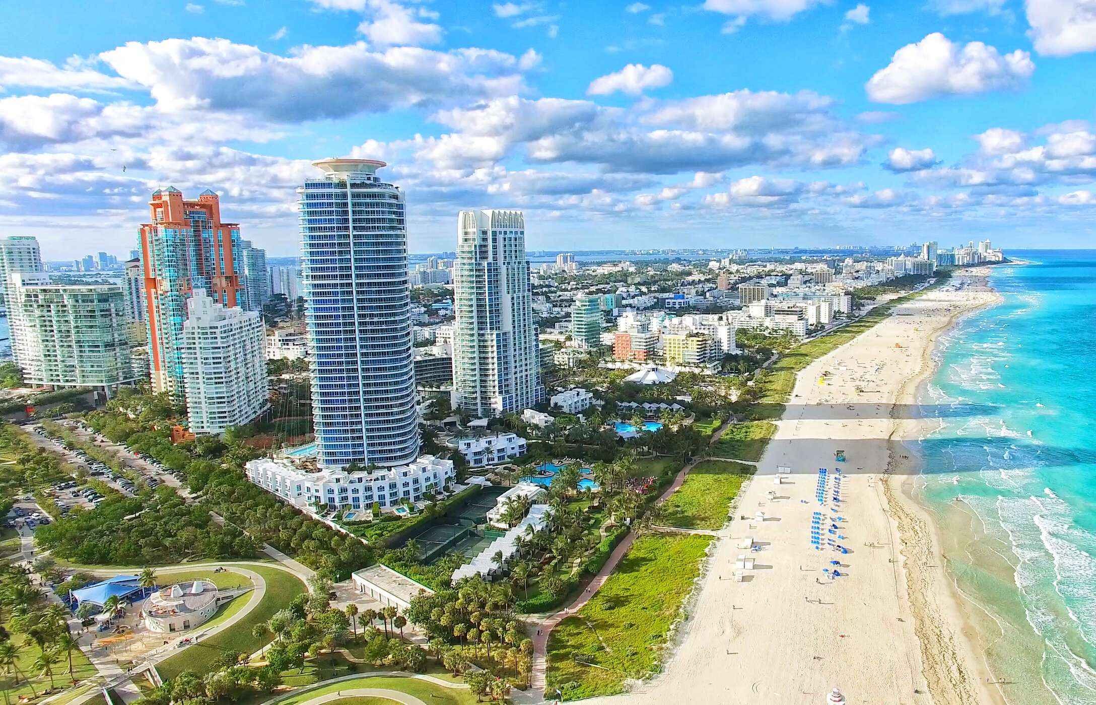 Uitzicht op het witte zandstrand in South Beach, met kristalhelder water en hoge gebouwen parallel aan het strand