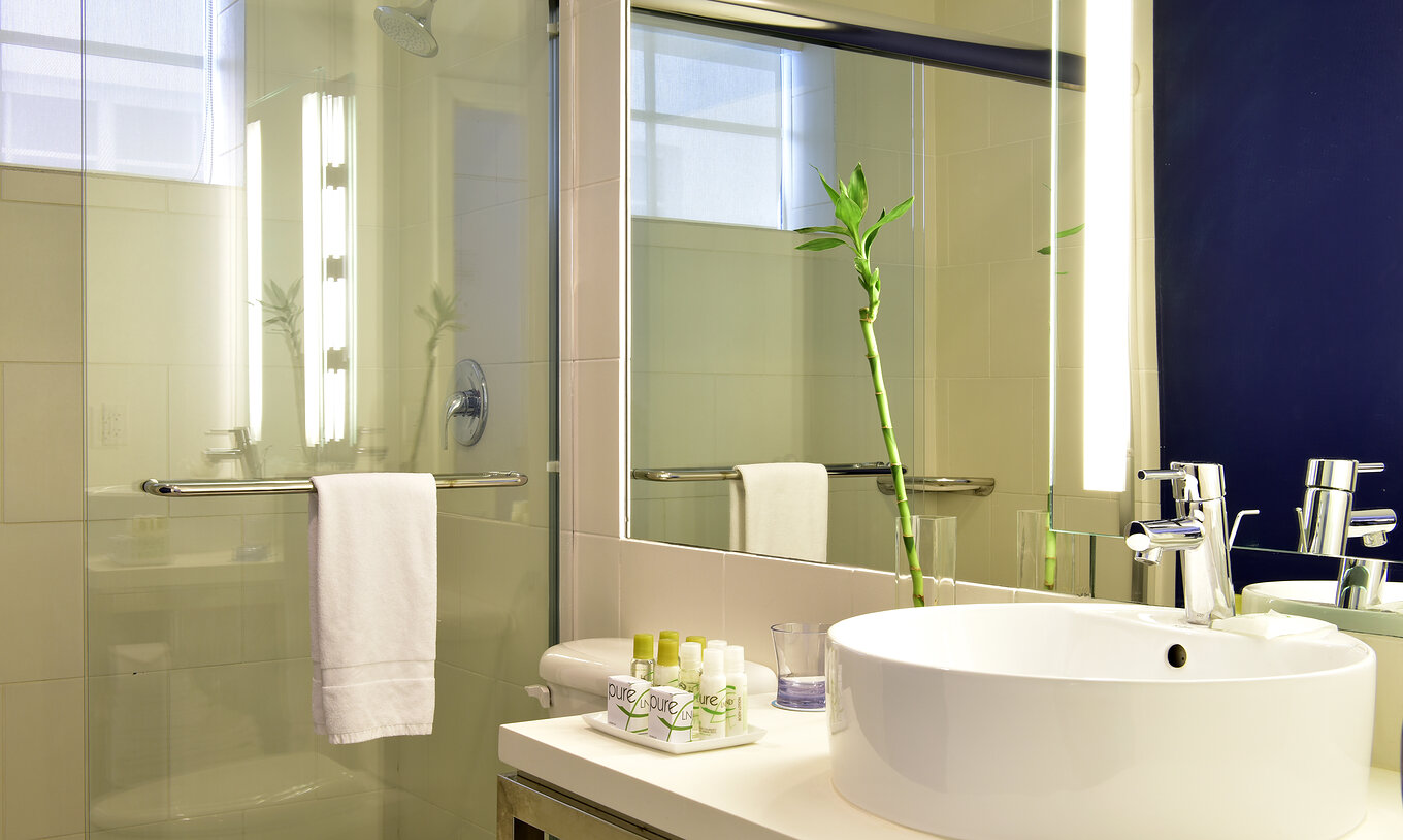 De Klassieke tweepersoonsbedden Van Pestana Miami South Beach Heeft Wastafel Spiegel Douche En Toilet