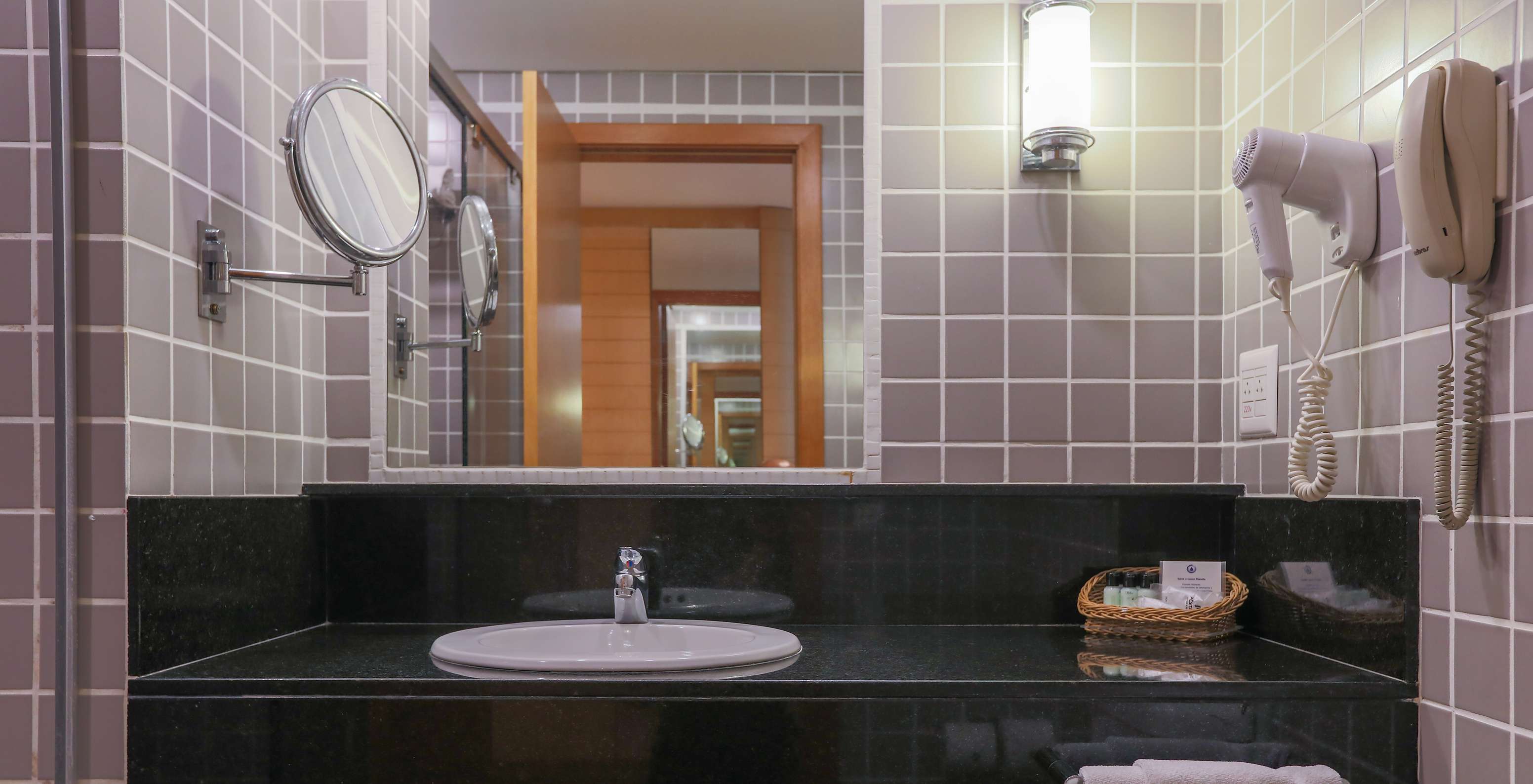 O Queen Standard do Pestana Curitiba tem uma casa de banho com azulejos cinzentos e uma bancada preta com lavatório