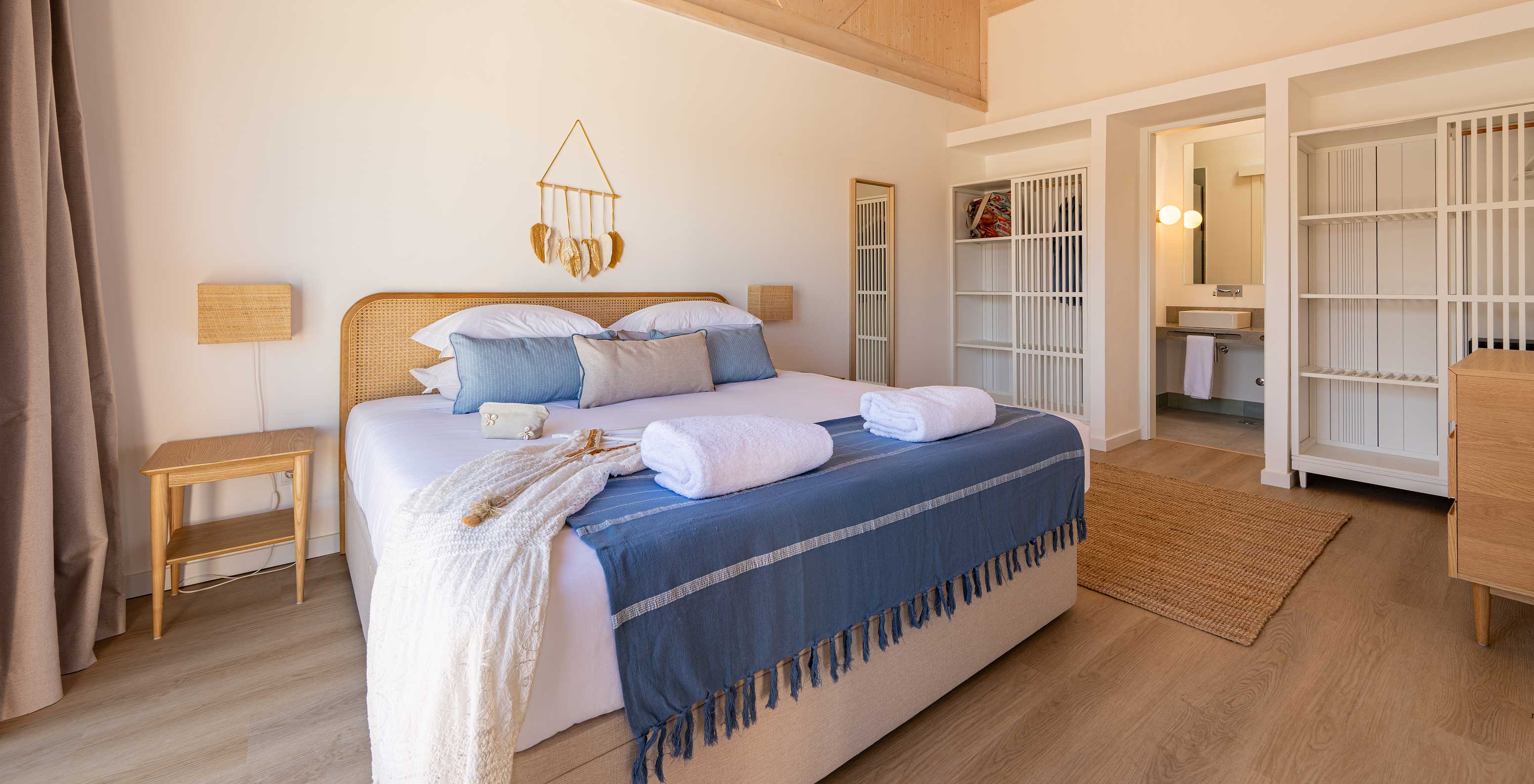 A Premium Villa do Pestana Comporta Village Residences tem um quarto com uma cama de casal e várias almofadas azuis