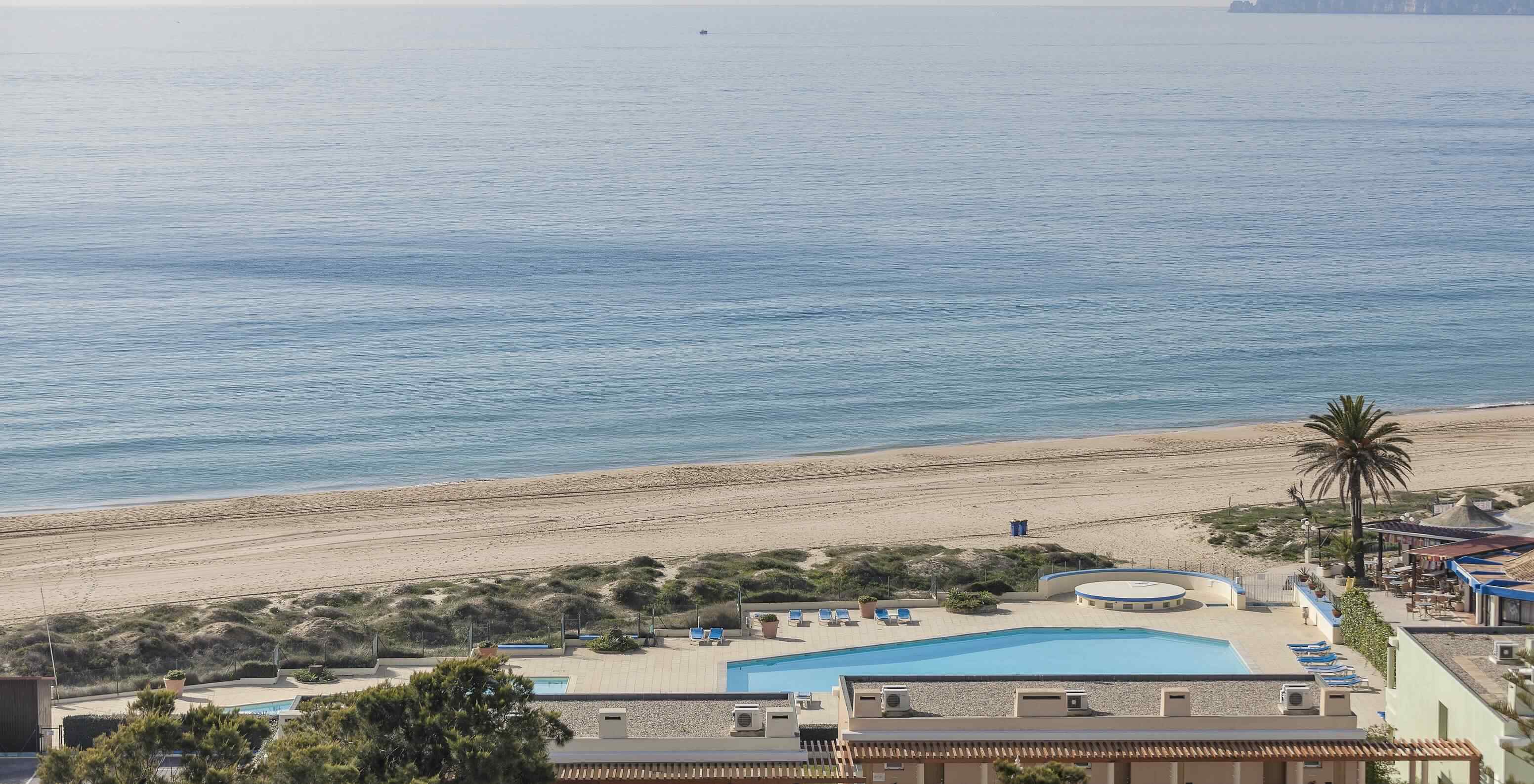 A Praia de Alvor, no Algarve, tem areia dourada e água cristalina, um passadiço e dunas