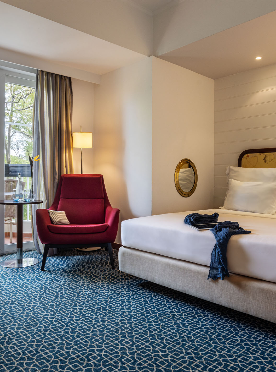 A Suite Vista Jardim do Pestana Alvor Praia tem cama de casal, cadeirão vermelho e varanda com vista jardim e cadeiras