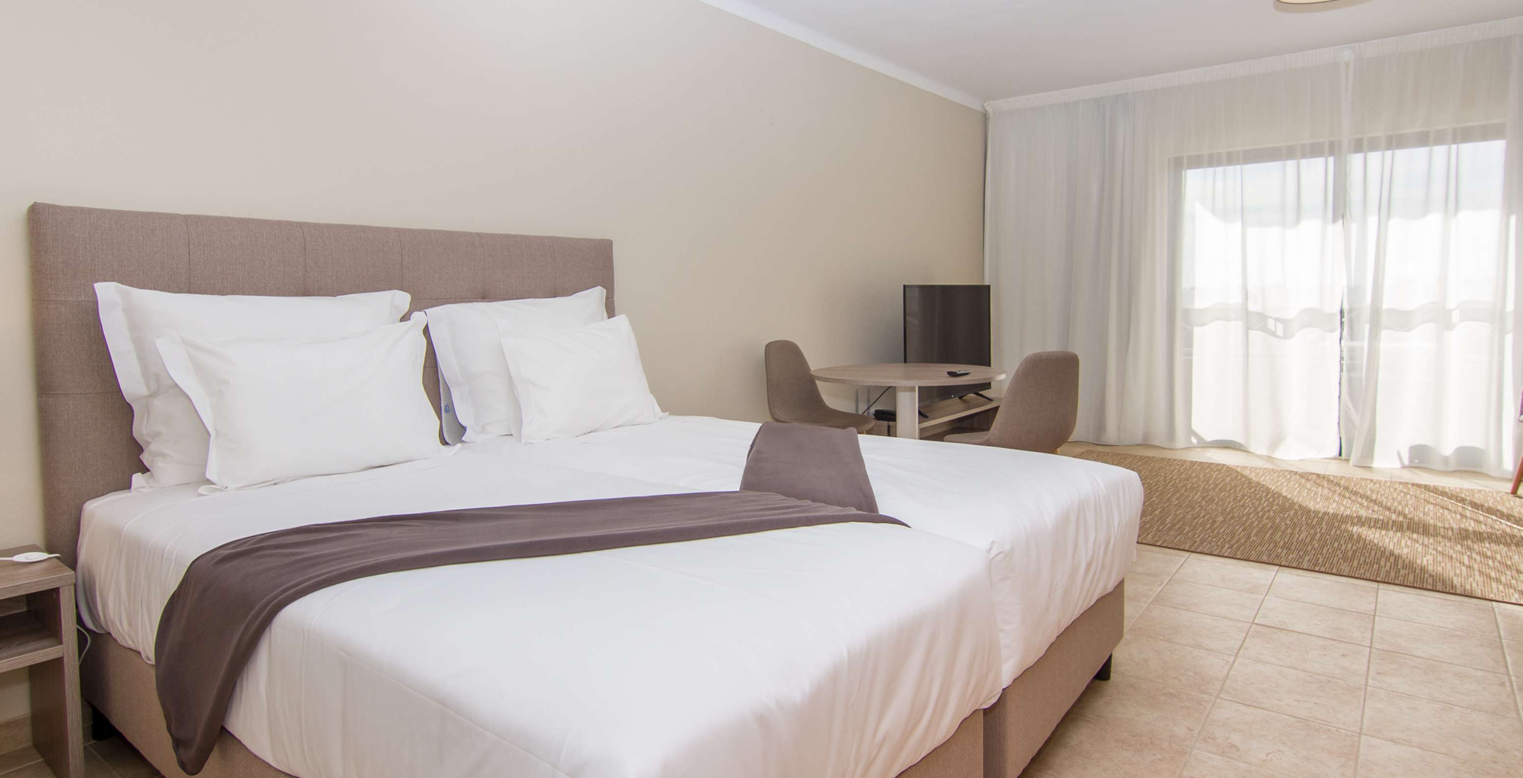 O Studio do Pestana Gramacho Residences tem duas camas individuais, uma mesa com duas cadeiras e uma janela