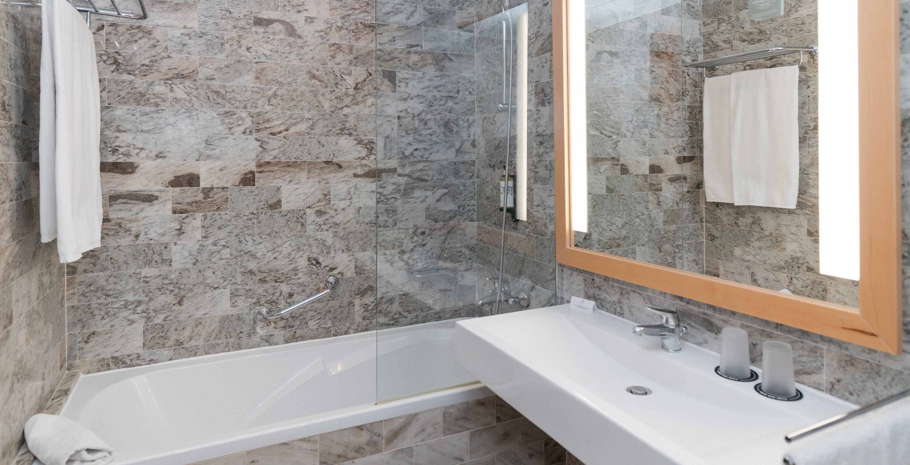 A Suite Superior Vista Mar do Pestana Viking tem uma casa de banho com lavatório com espelho grande e uma banheira com duche