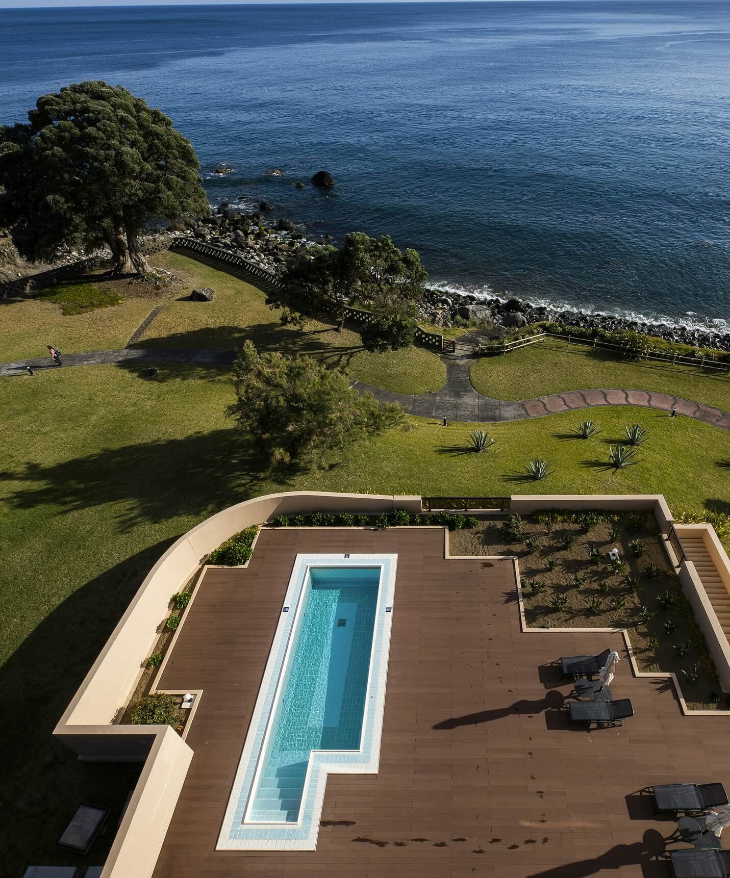 Piscina do Pestana Bahia Praia sobre deck de madeira com vista para o mar e zona verde envolvente