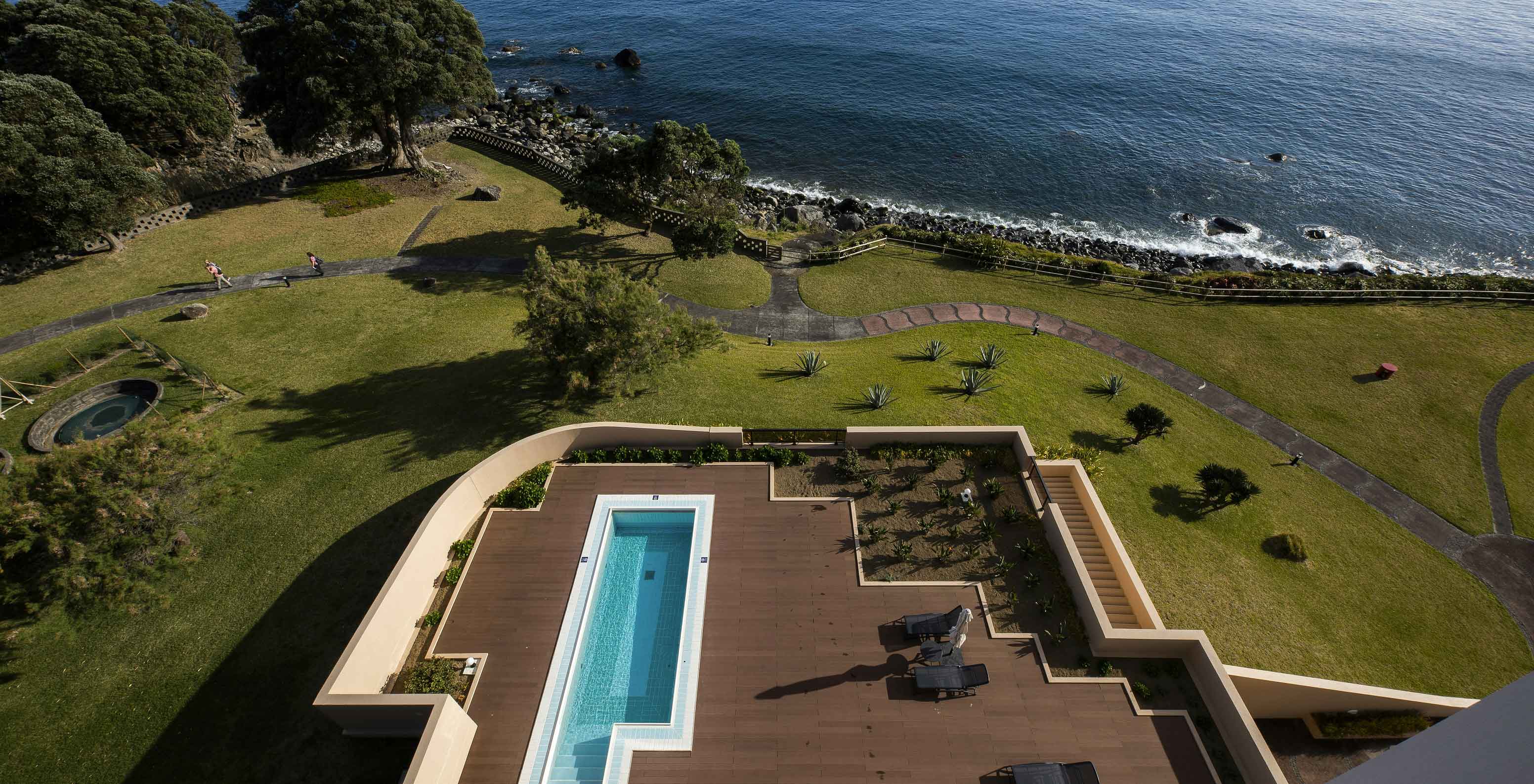 Piscina do Pestana Bahia Praia sobre deck de madeira com vista para o mar e zona verde envolvente