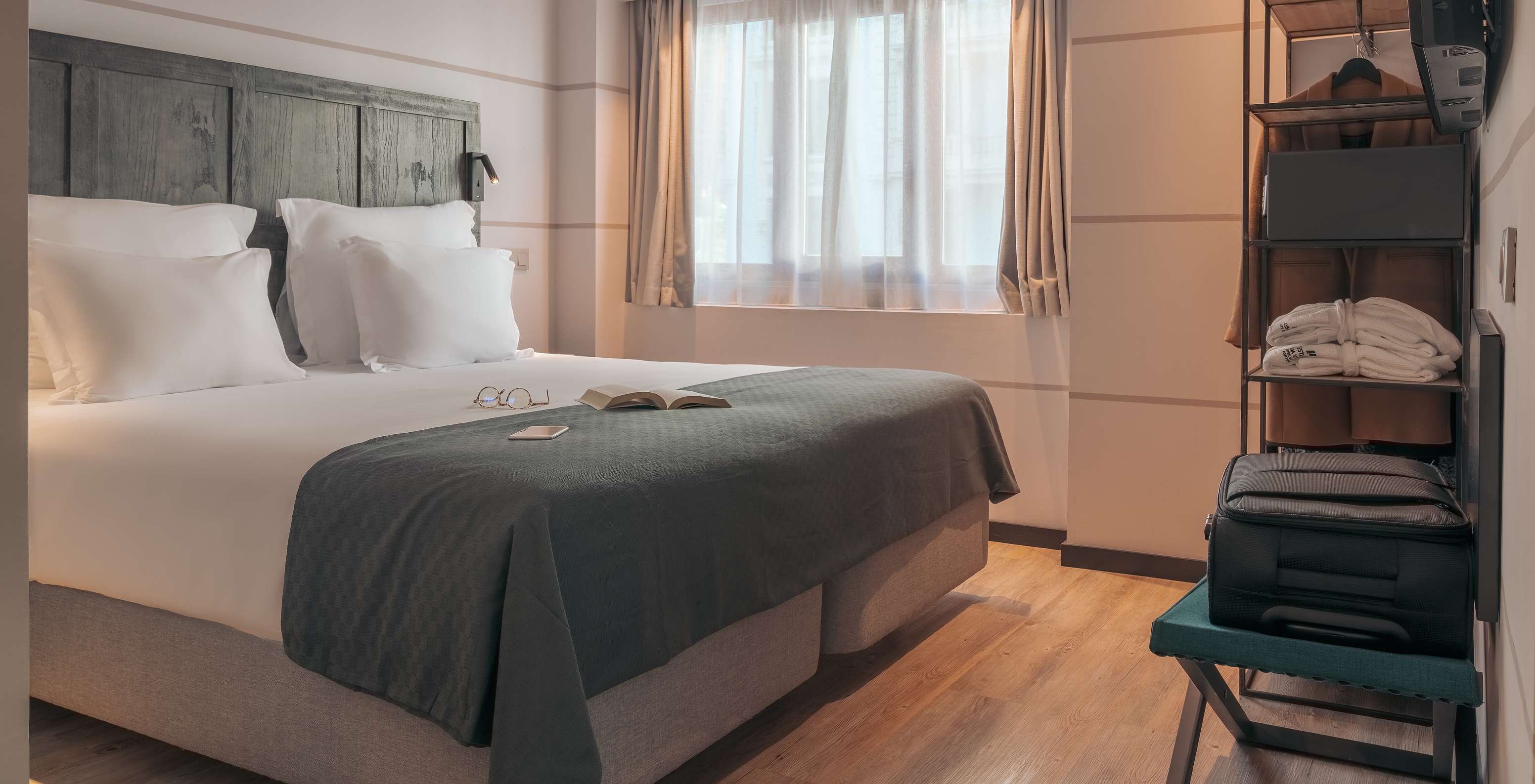 O Double Deluxe Studio do Pestana Lisboa Vintage tem uma cama de casal com uma manta cinzenta e um armário com um casaco