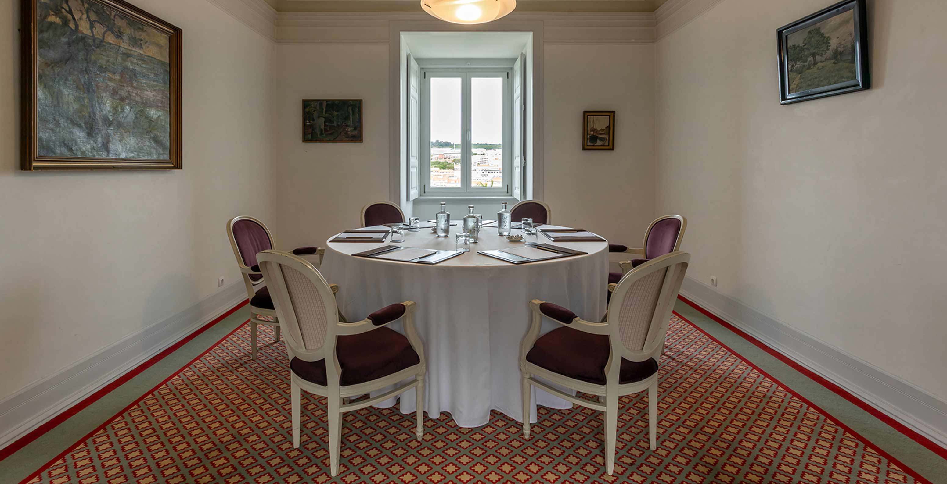 O Pestana Palace Lisboa tem uma sala de reuniões com uma mesa redonda branca rodeada de cadeiras roxas