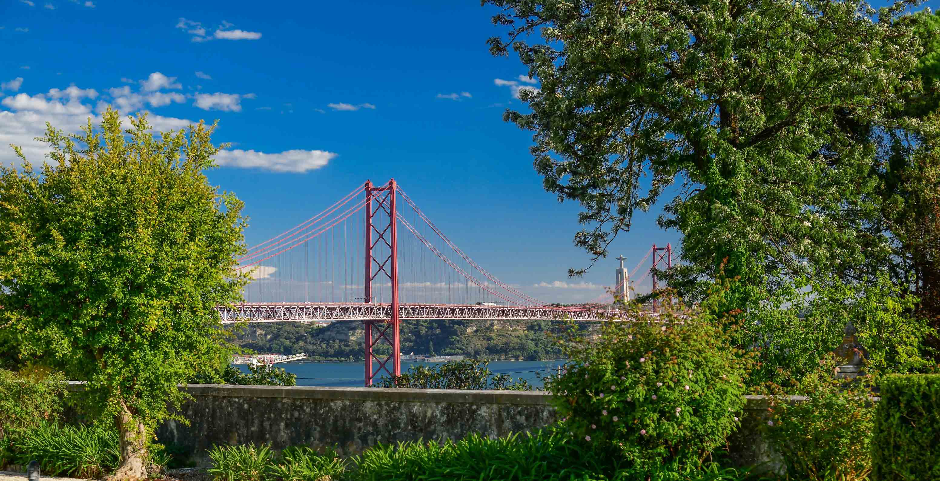 Vista do Pestana Palace Lisboa para a ponte 25 de Abril e para o Rio Tejo, com várias árvores pelo meio