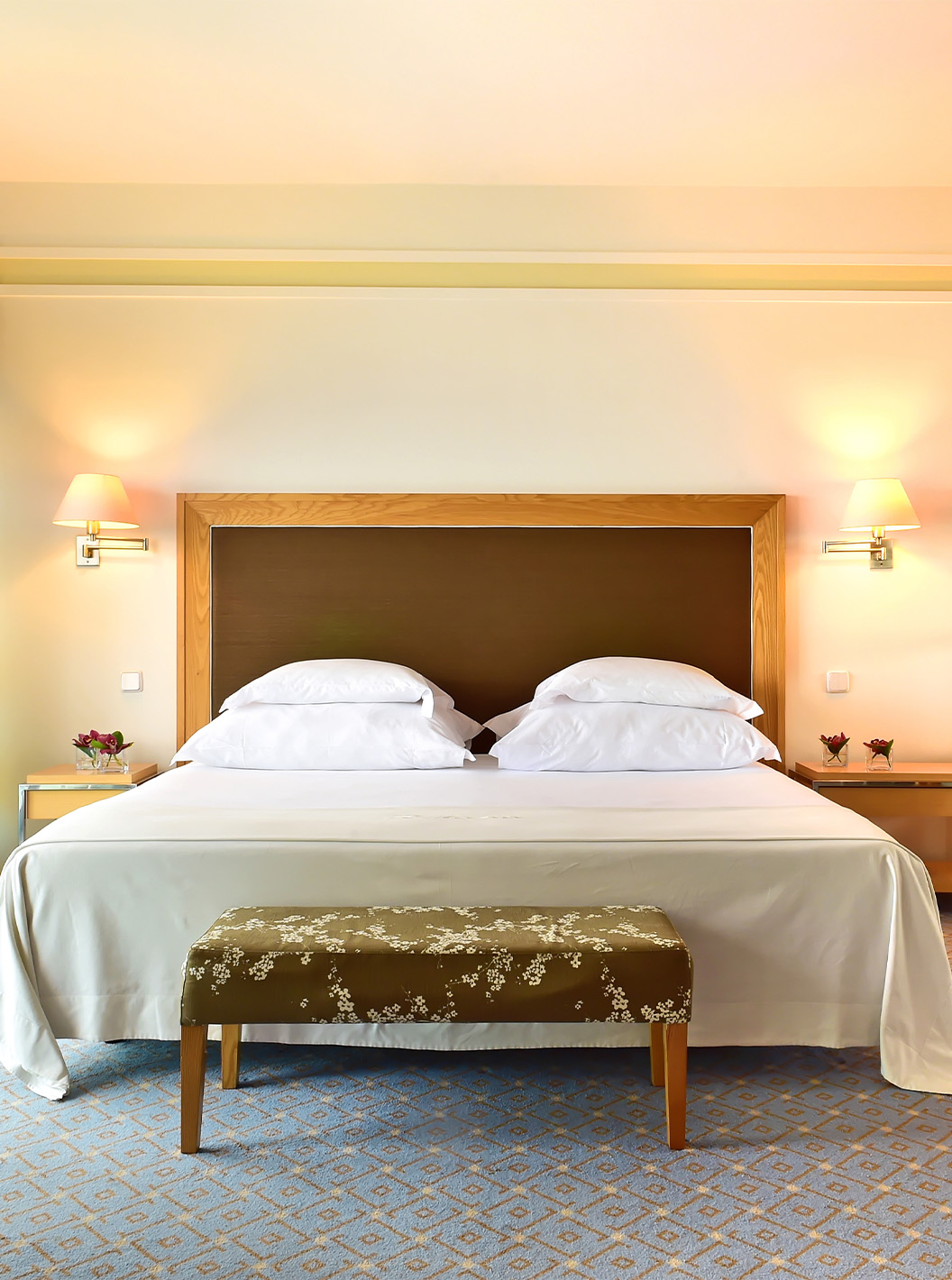 A Junior Suite do Pestana Carlton Madeira tem uma cama de casal com um banco nos pés e um armário com espelhos