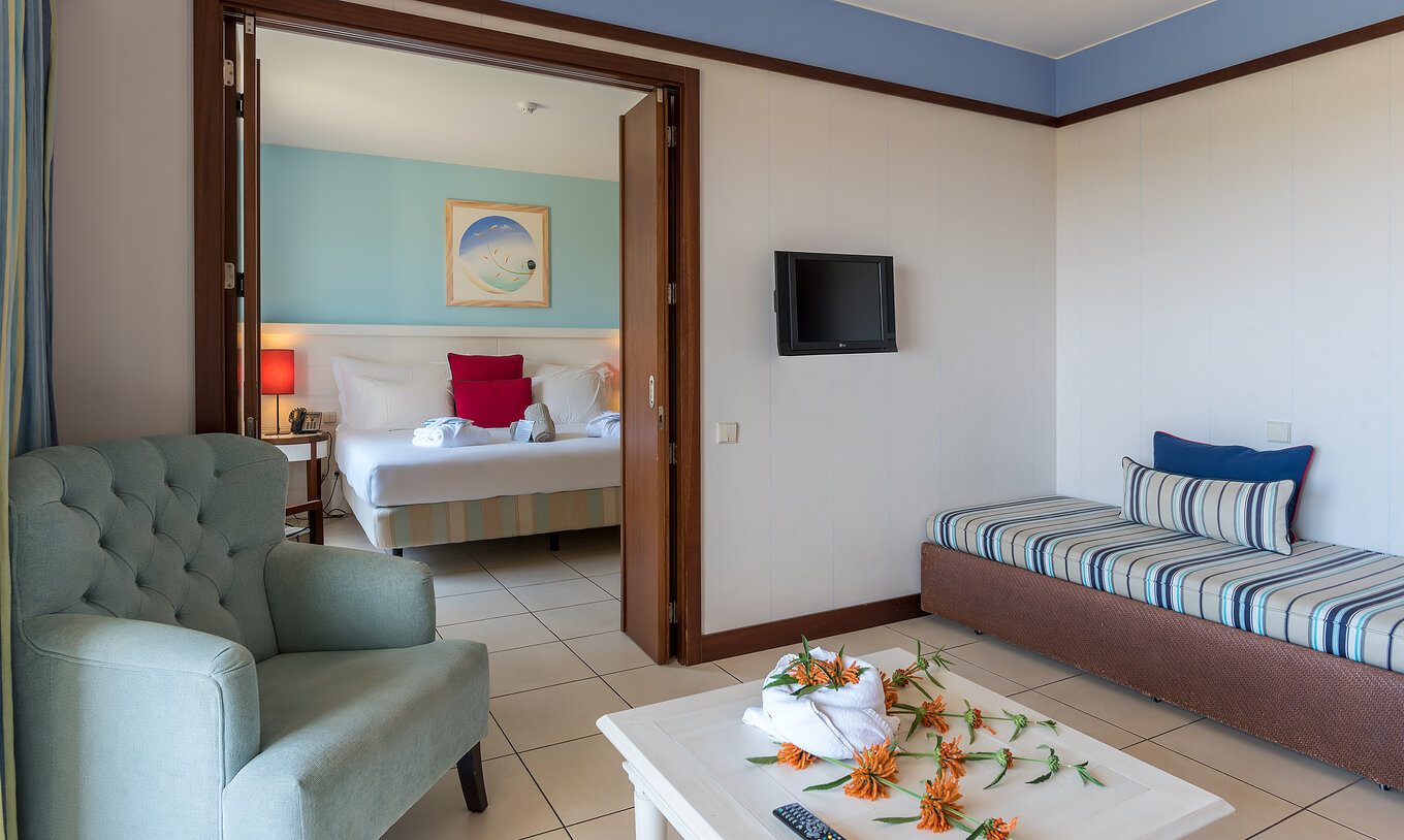 A Suite Apartamento T1 do Pestana Porto Santo All Inclusive tem um quarto com cama de casal e uma sala com sofá e televisão