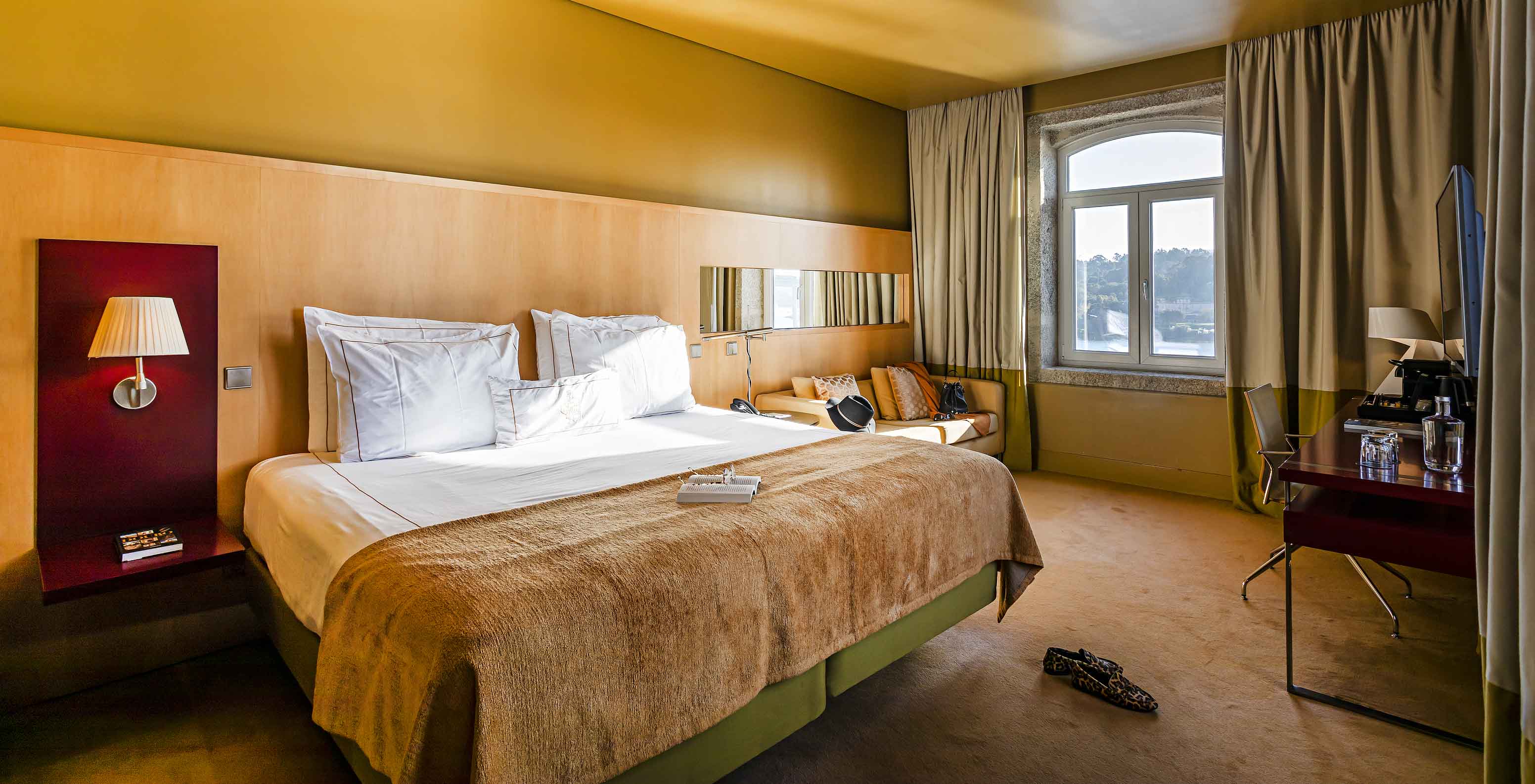 O Deluxe Grand View do Pestana Palácio do Freixo tem uma cama de casal e uma janela em pedra com vista para o rio Douro