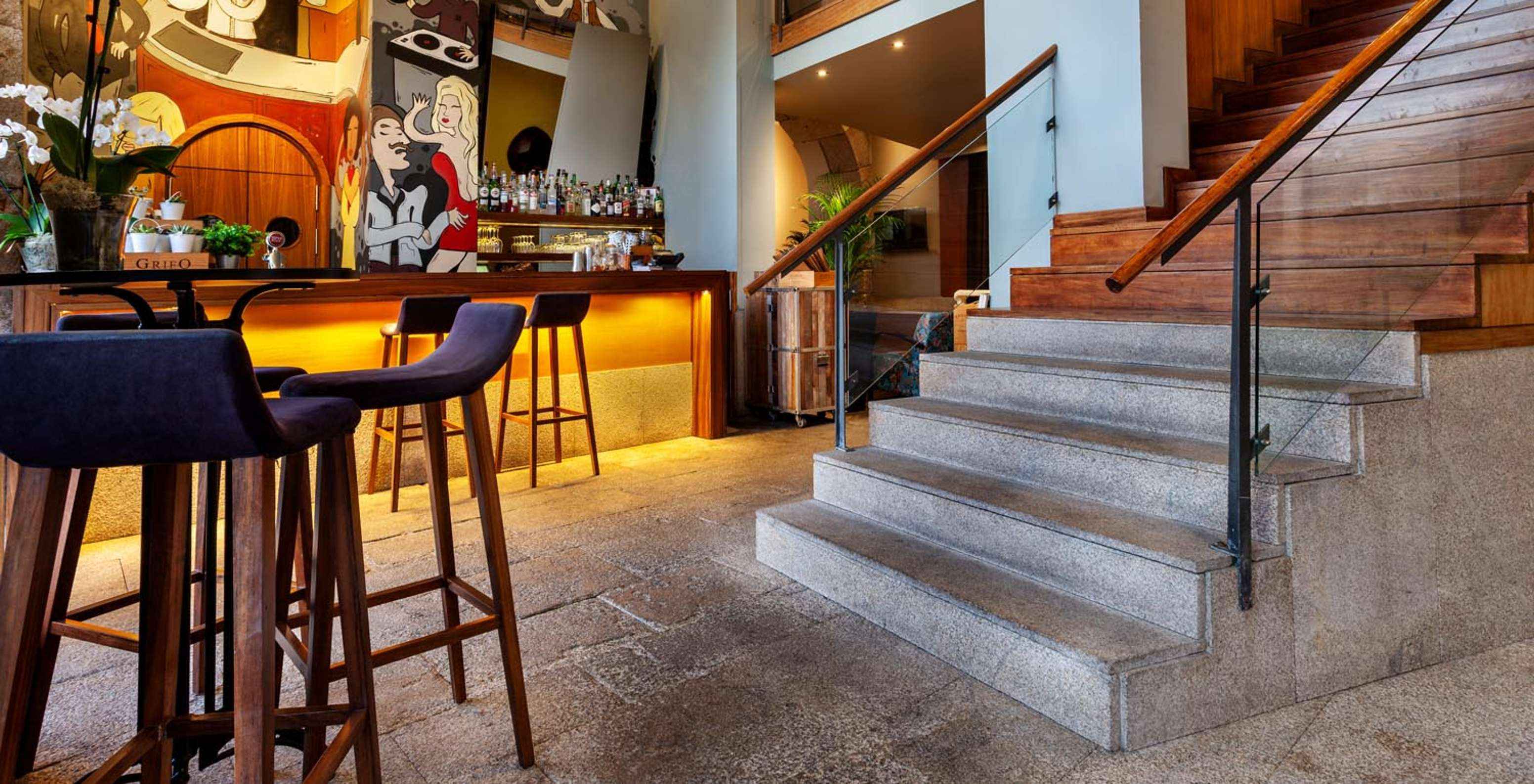 Bar com paredes com desenhos, ao pé das escadas do Pestana Vintage Porto, um Hotel na Praça da Ribeira, no Porto