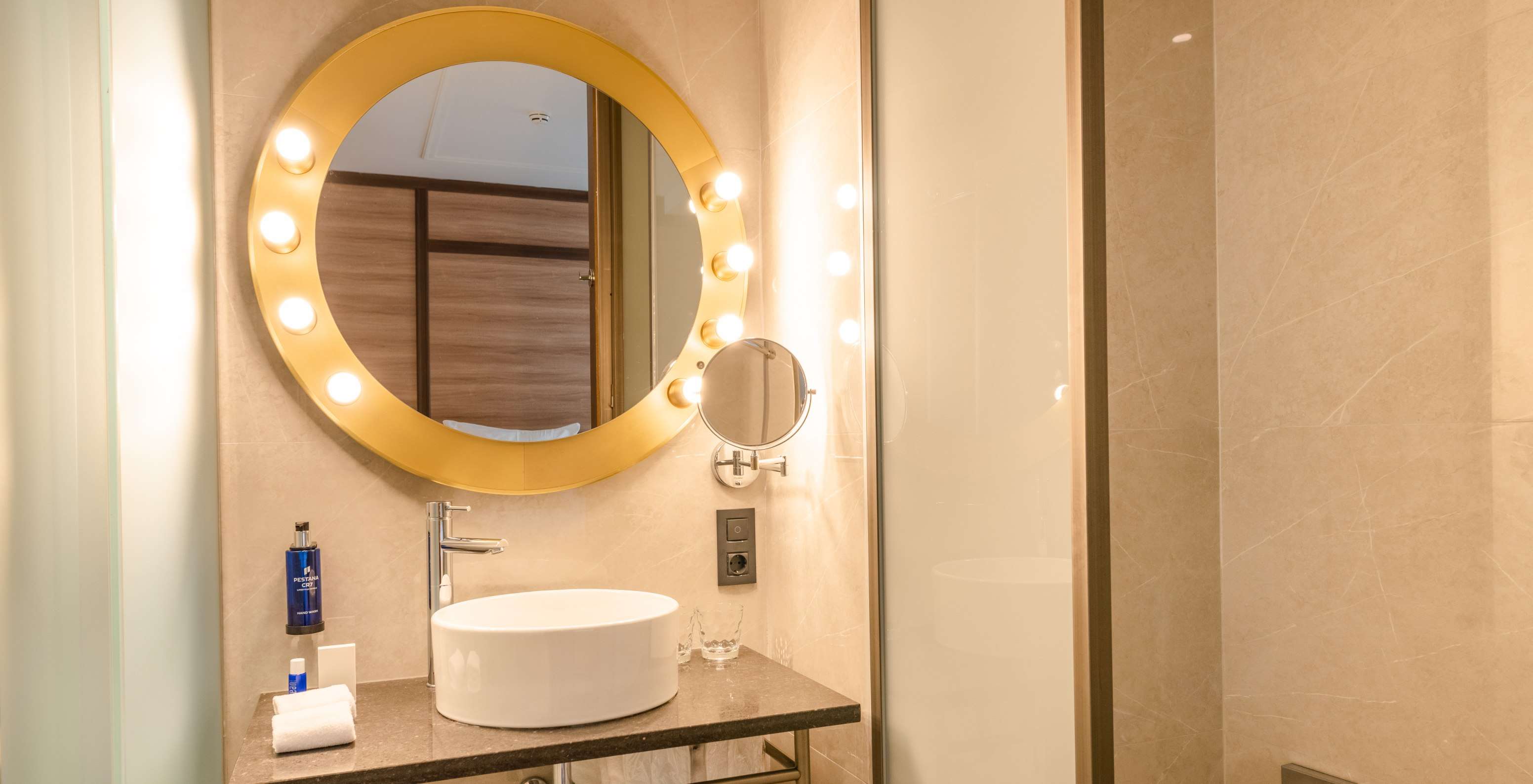 O Cozy Room do Pestana CR7 Gran Vía Madrid tem uma casa de banho com um espelho redondo com luzes