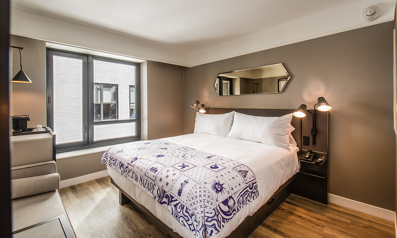 O quarto Clássico do Pestana Park Avenue conta com uma cama de casal, com mesa de cabeceira com candeeiro e telefone