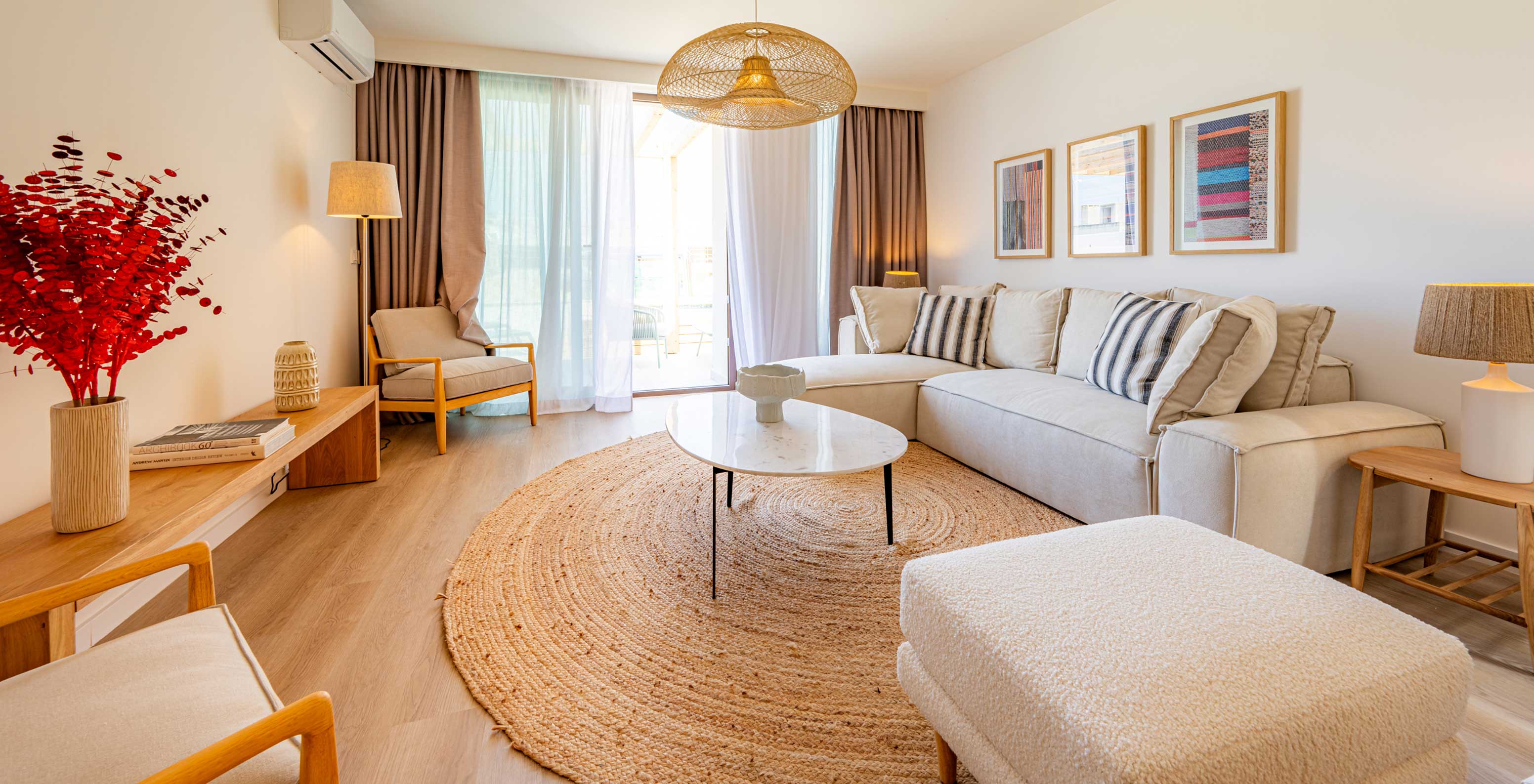 Sala de estar luminosa no Pestana Porto Covo Village, com sofá bege, mesa redonda e decoração moderna